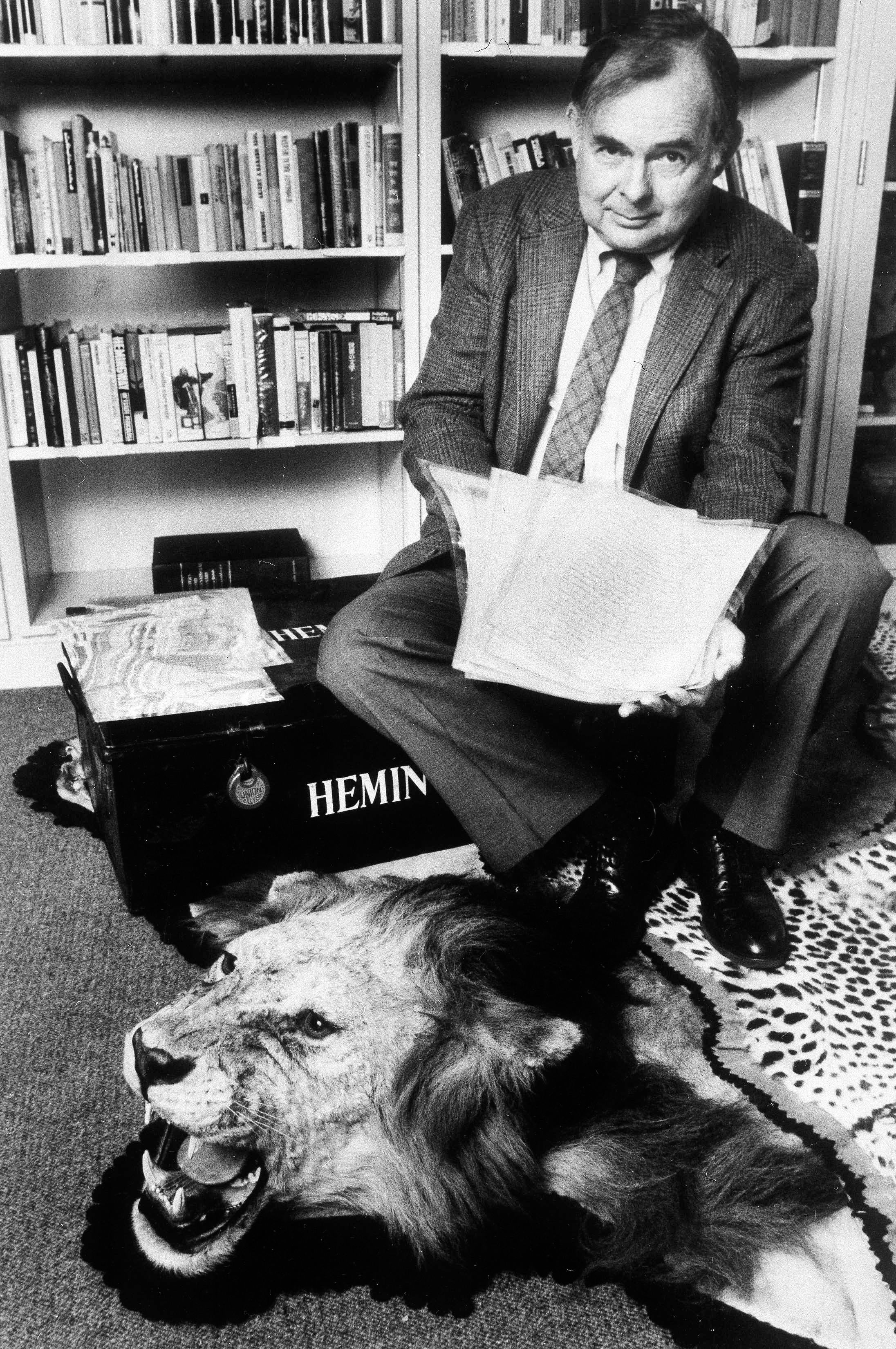 Patrick Hemingway, the second of Nobel laureate Ernest Hemingway's three sons, poses at the John F. Kennedy Library with a boat log kept by Hemingway during a fishing expedition in Cuba and a lion skin from a lion Hemingway hunted and killed in Boston, May 17, 1989. (AP Photo/Scott Maguire, File)