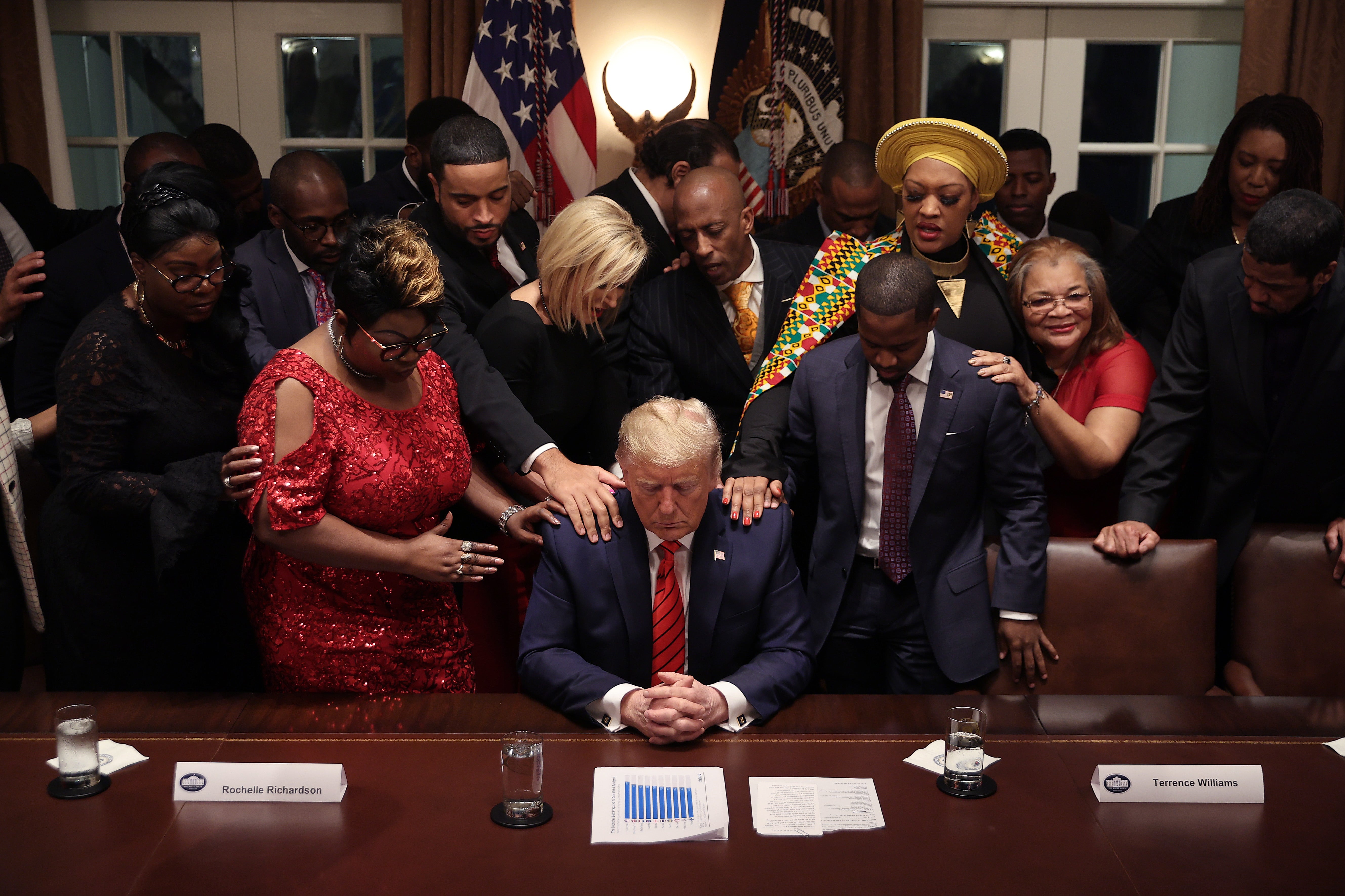 Supporters lay their hands on President Donald Trump as they pray for him at the conclusion of a news conference in February 2020
