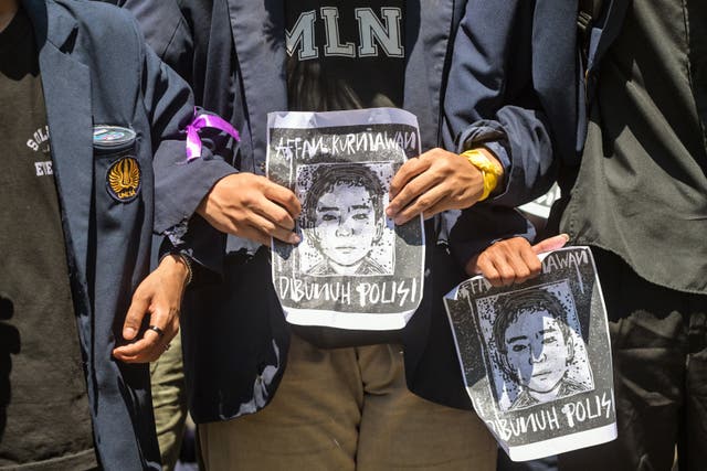 <p>Protesters hold portraits of Affan Kurniawan in front of the regional police headquarters in Surabaya</p>