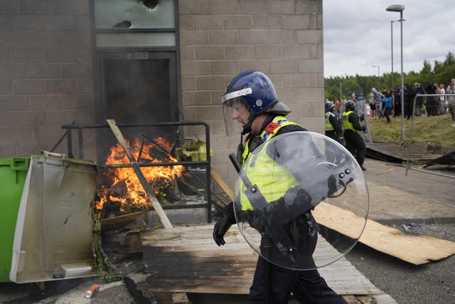 <p>A police officer walks past a fire as trouble flares during an anti-immigration protest in Rotherham </p>