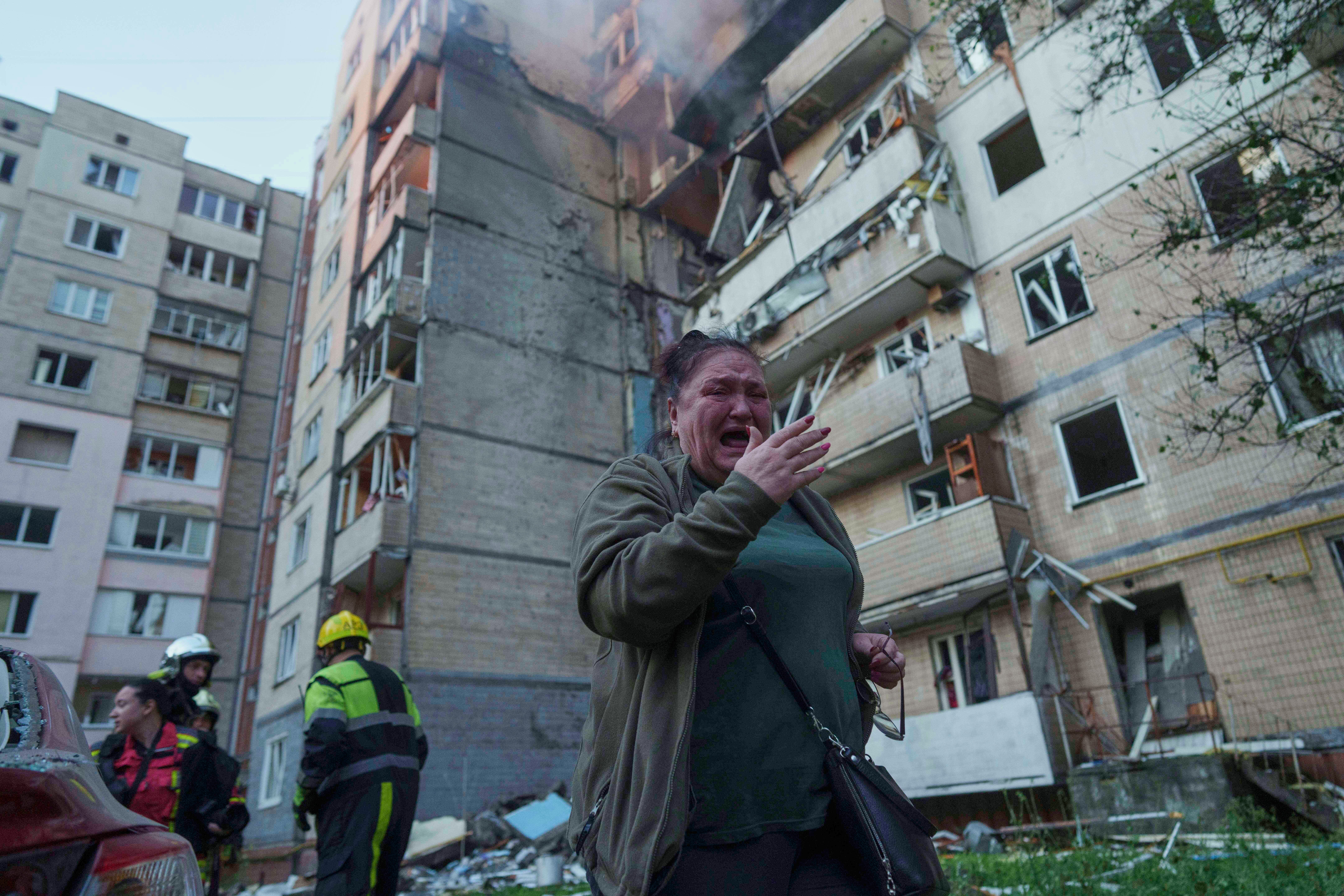 A woman reacts outside a damaged building in Kyiv