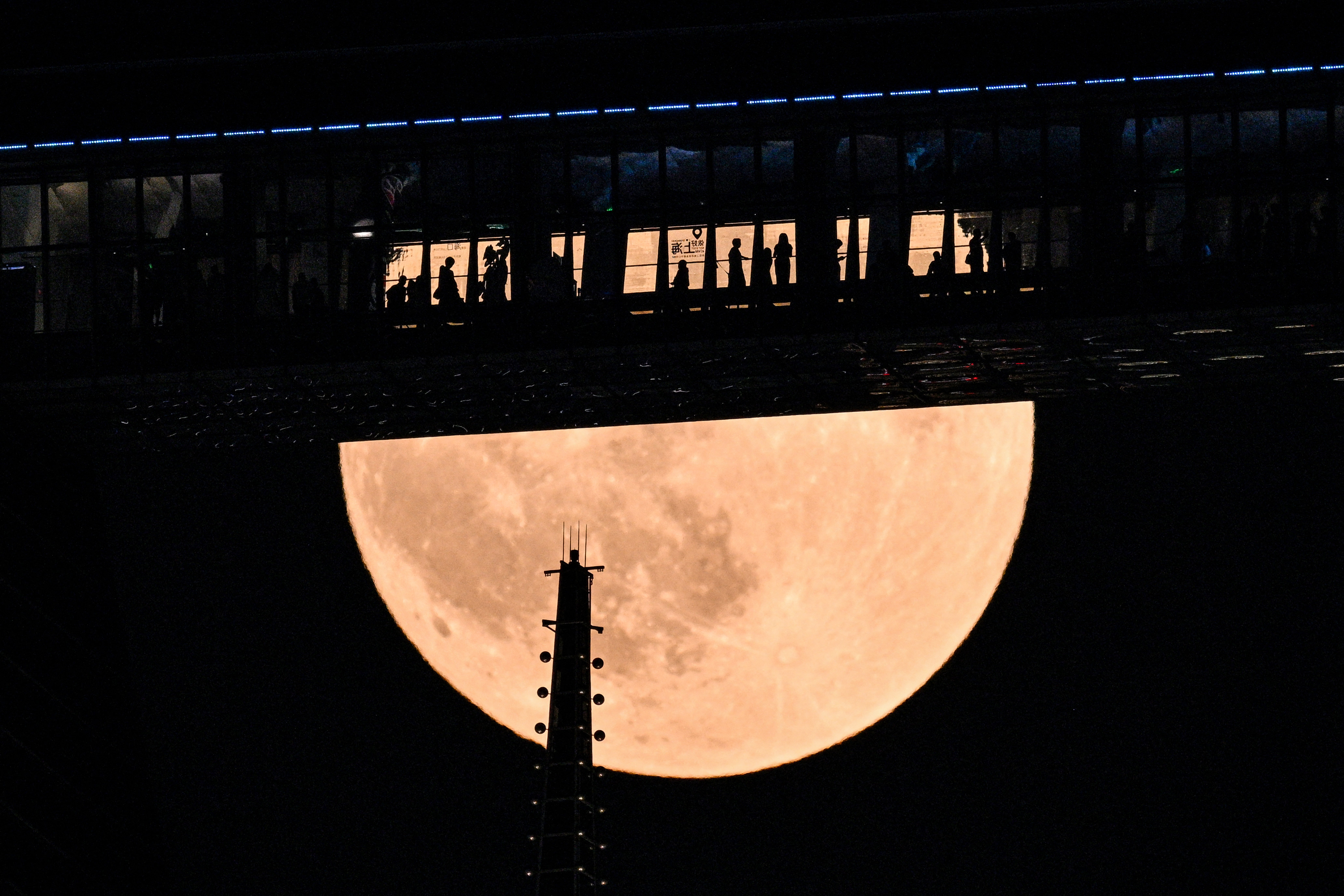 People are seen on a floor of the Shanghai World Financial Centre as a full moon, also known as the 