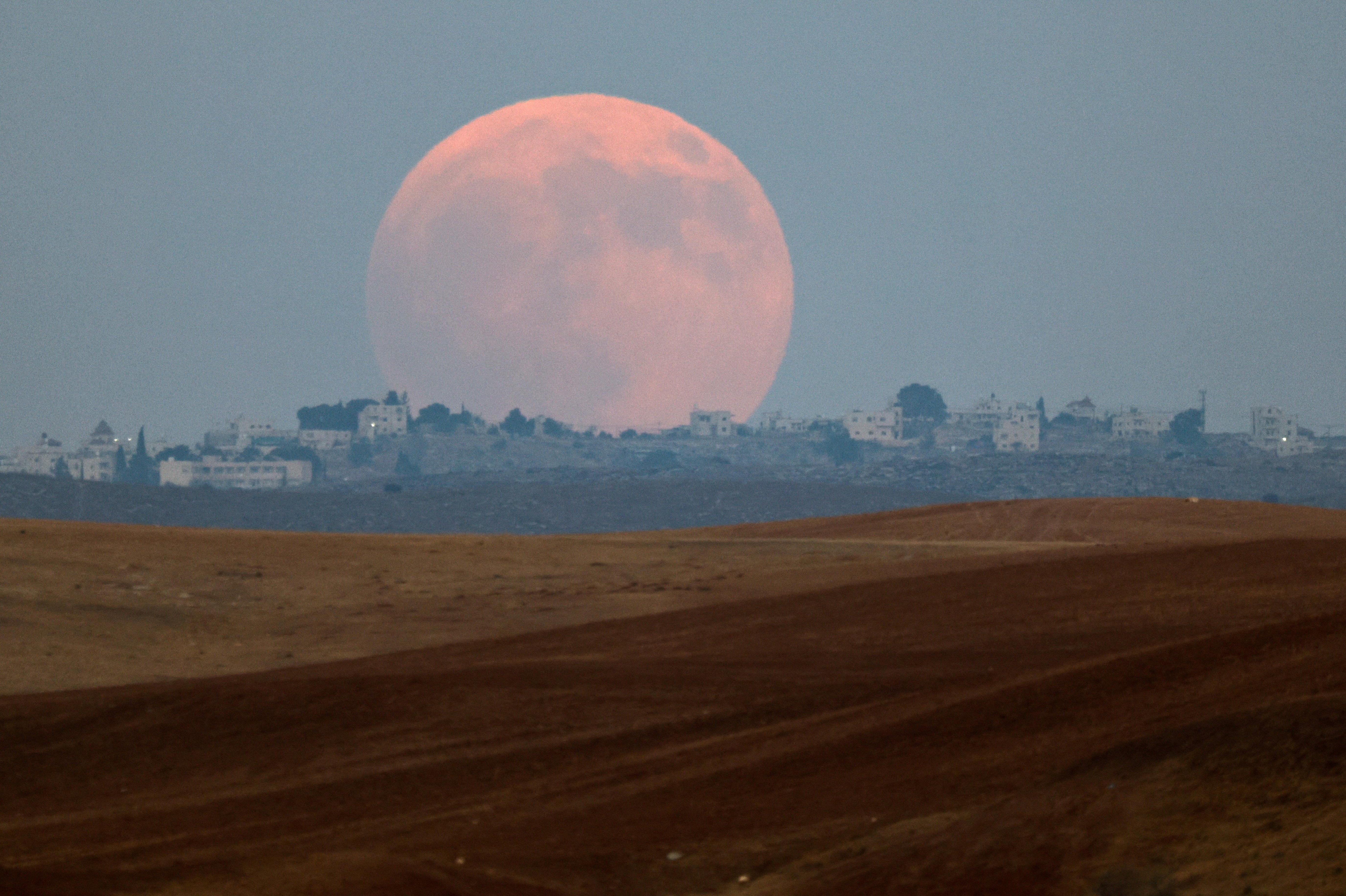 The ‘Blood Moon’ rises over the West Bank, as seen from the Negev desert in Israel