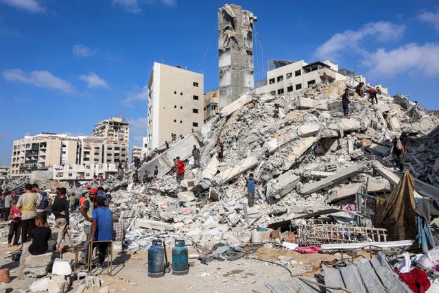<p>People search for salvage at the mound of rubble at the site of the collapsed Sussi Tower, which was destroyed earlier by Israeli bombardment, in Gaza City</p>