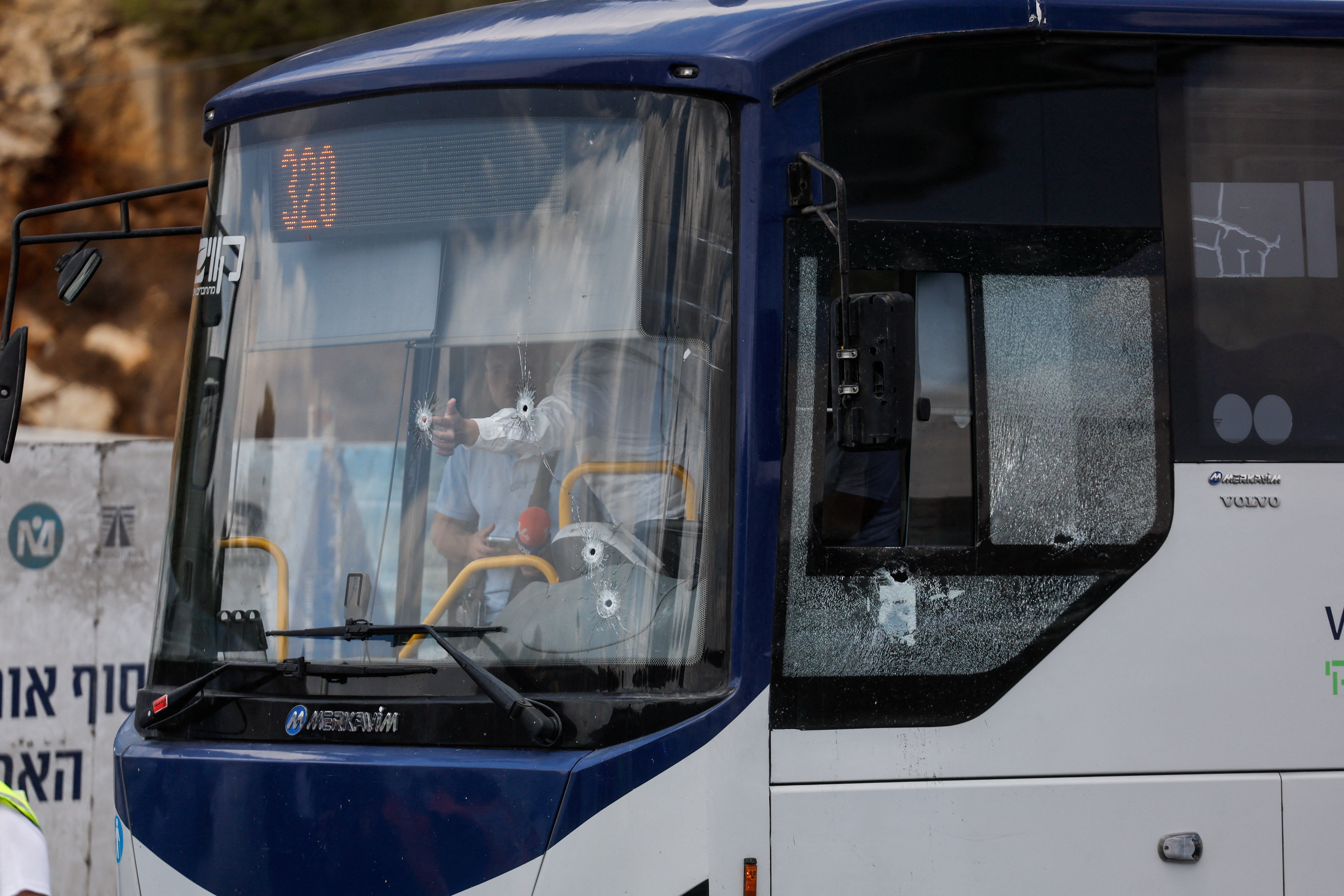 People inspect a bus with bullet holes