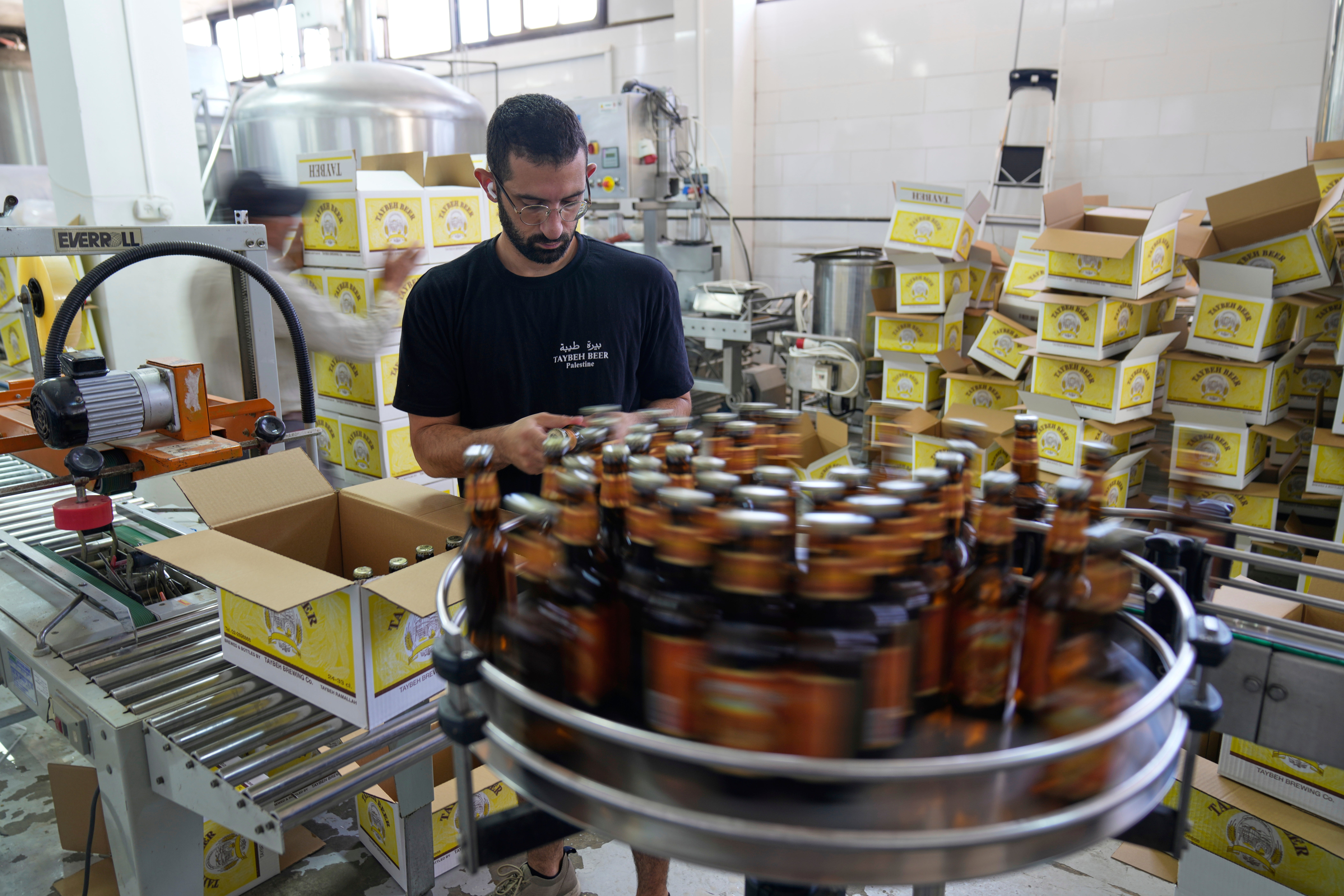 Canaan Khoury packs Taybeh beer bottles into boxes on a production line of the family's Palestinian Taybeh Brewery Co