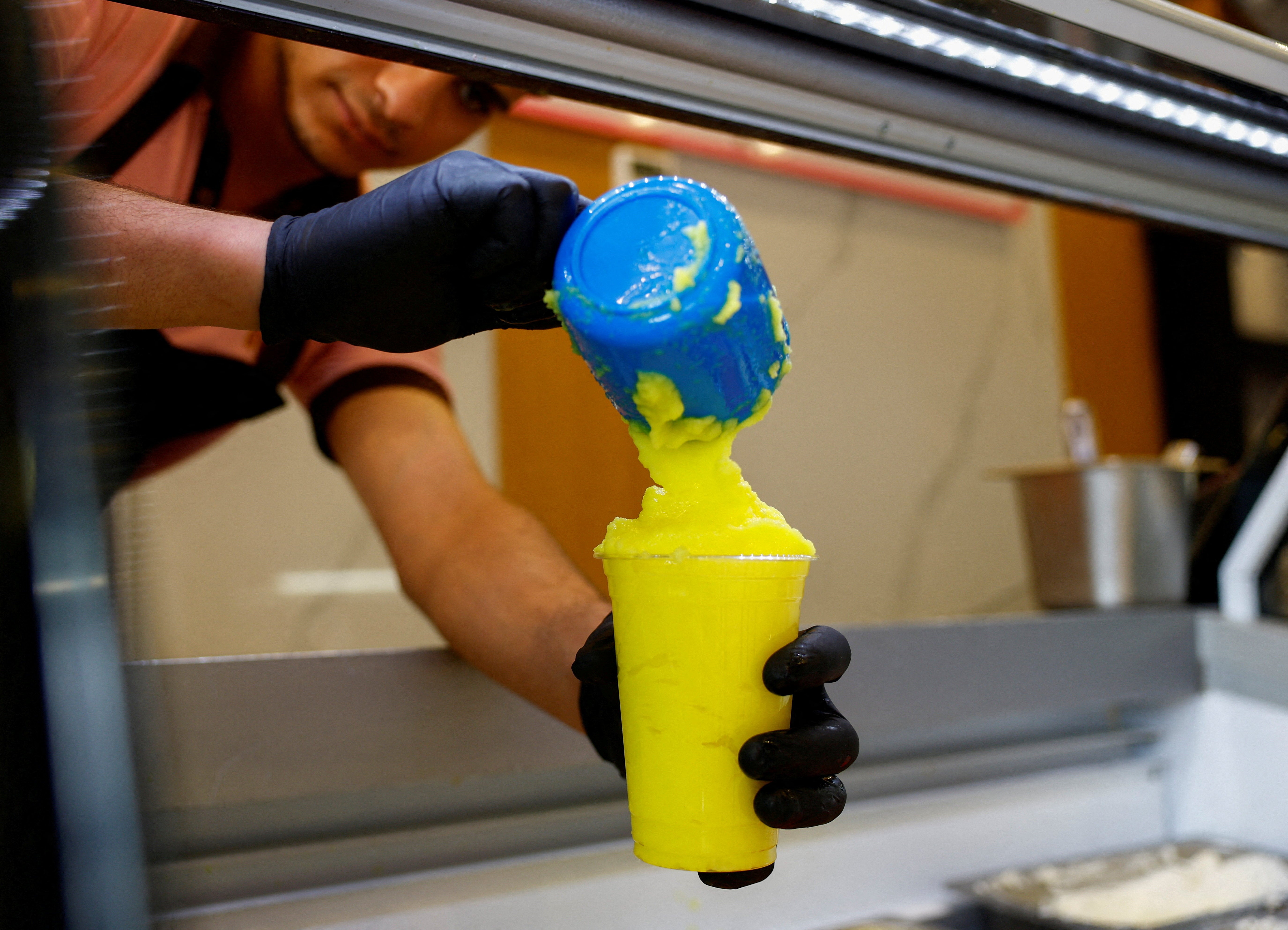 A worker fills a cup of