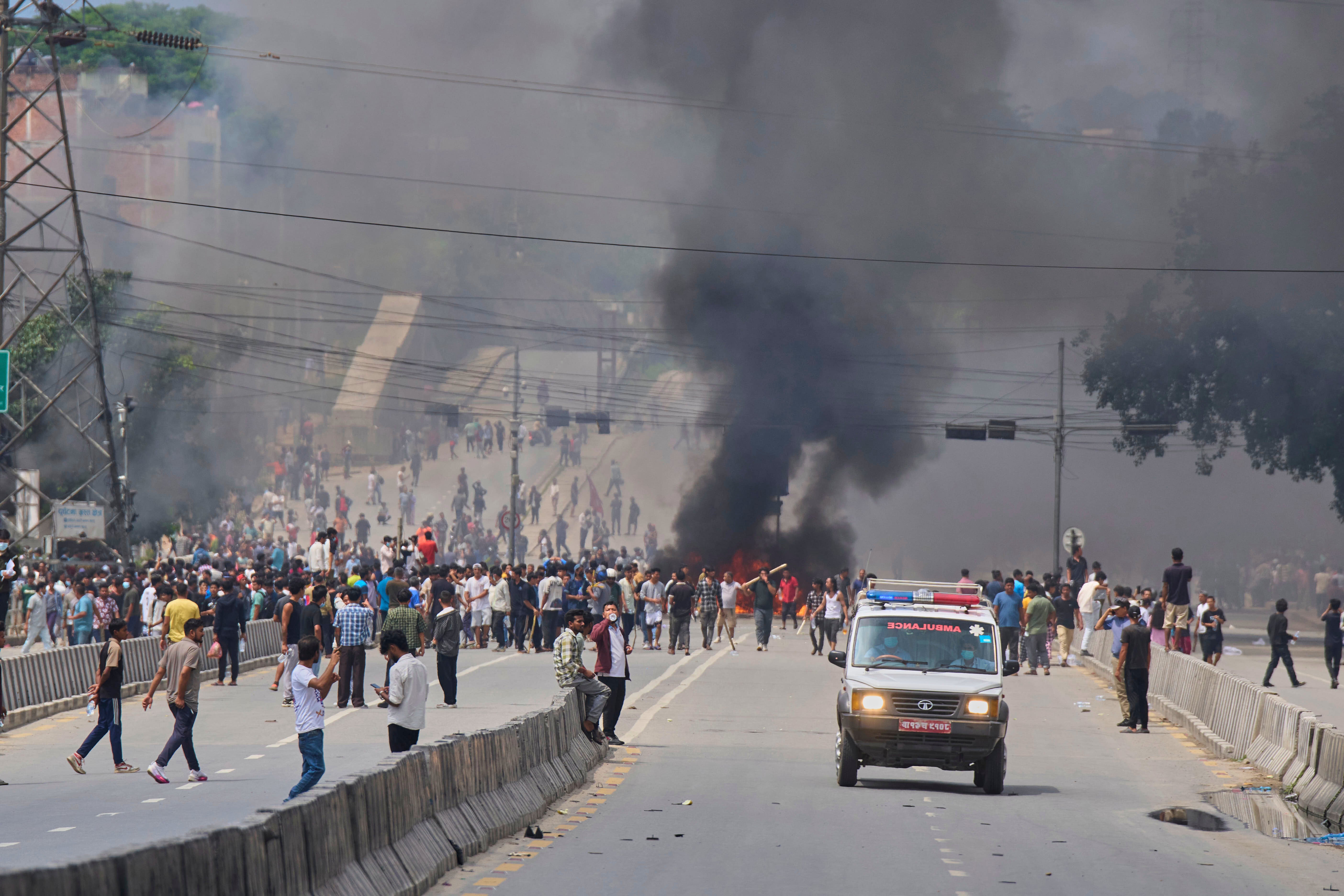 An ambulance drives past protesters burning tires to block streets during the demonstrations on Tuesday
