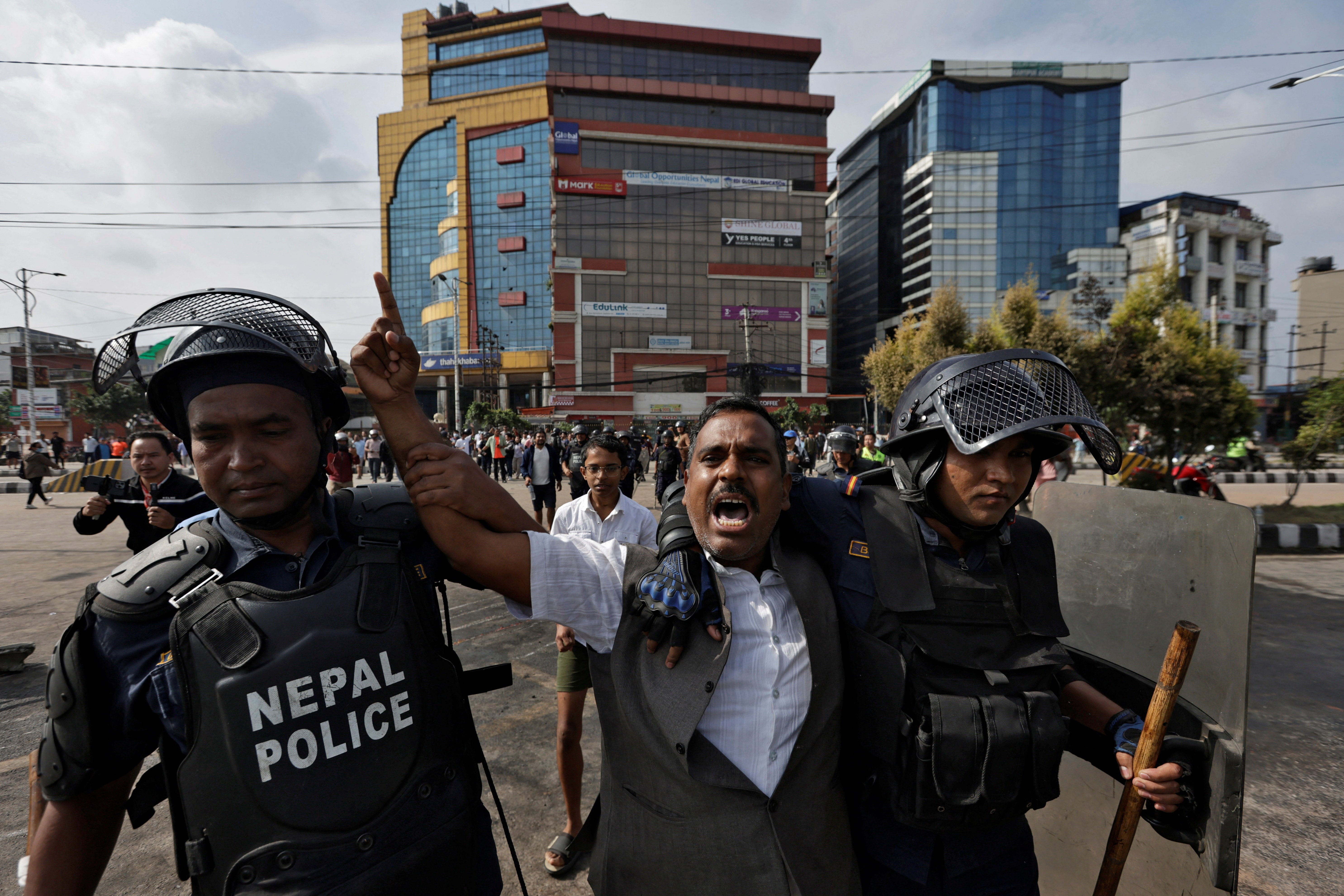 A demonstrator reacts as he is detained by police officers outside the parliament building in Kathmandu during a curfew