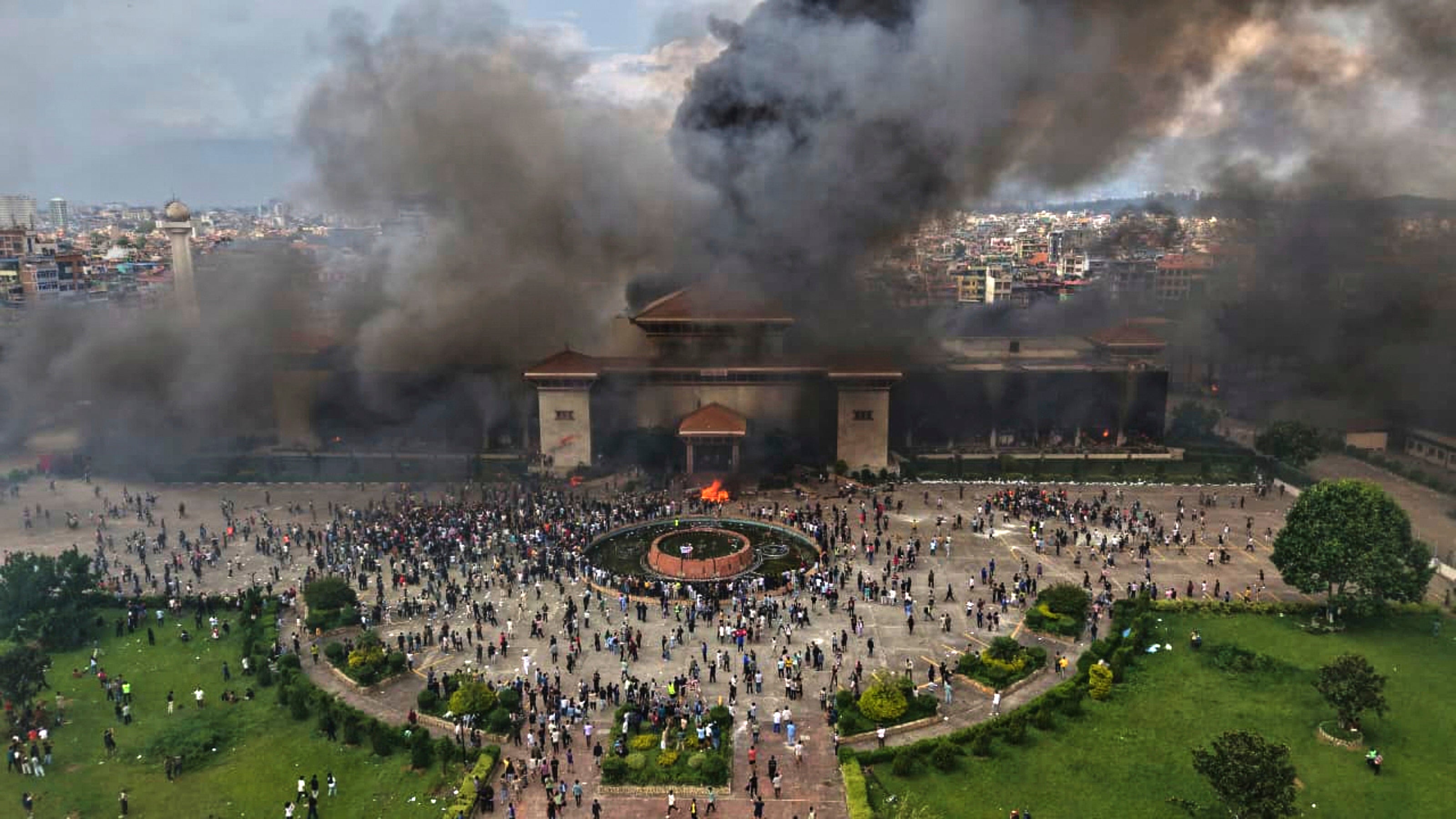 Protesters celebrate at the parliament building after it was set on fire