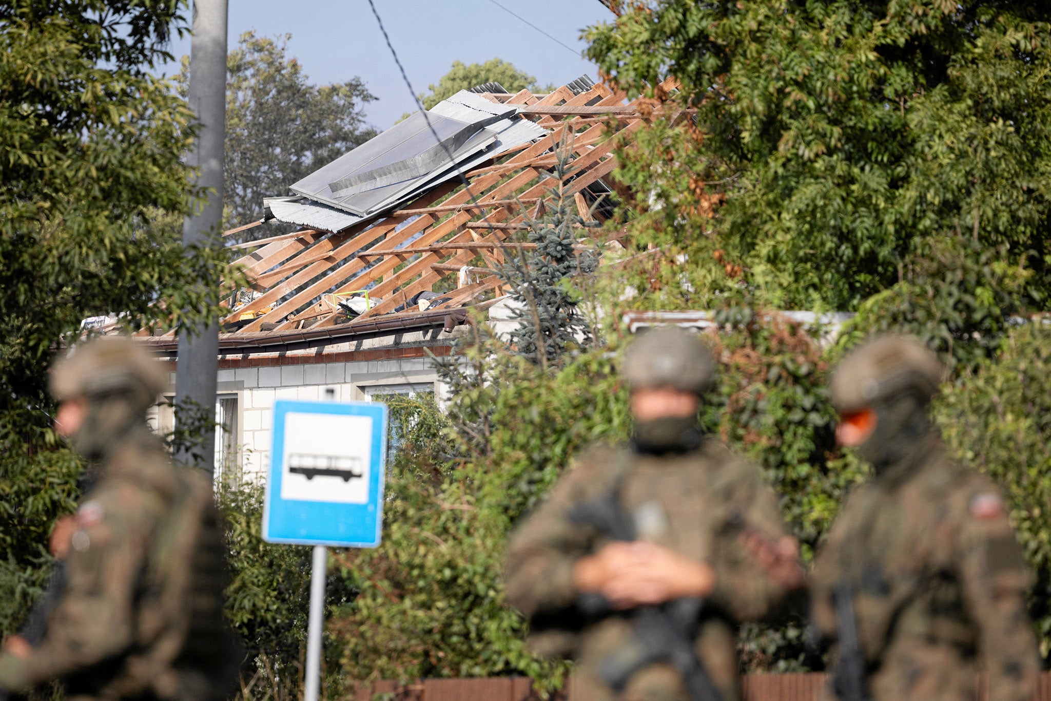 Soldiers patrol the street after a drone or similar object struck a residential building in Wyryki municipality