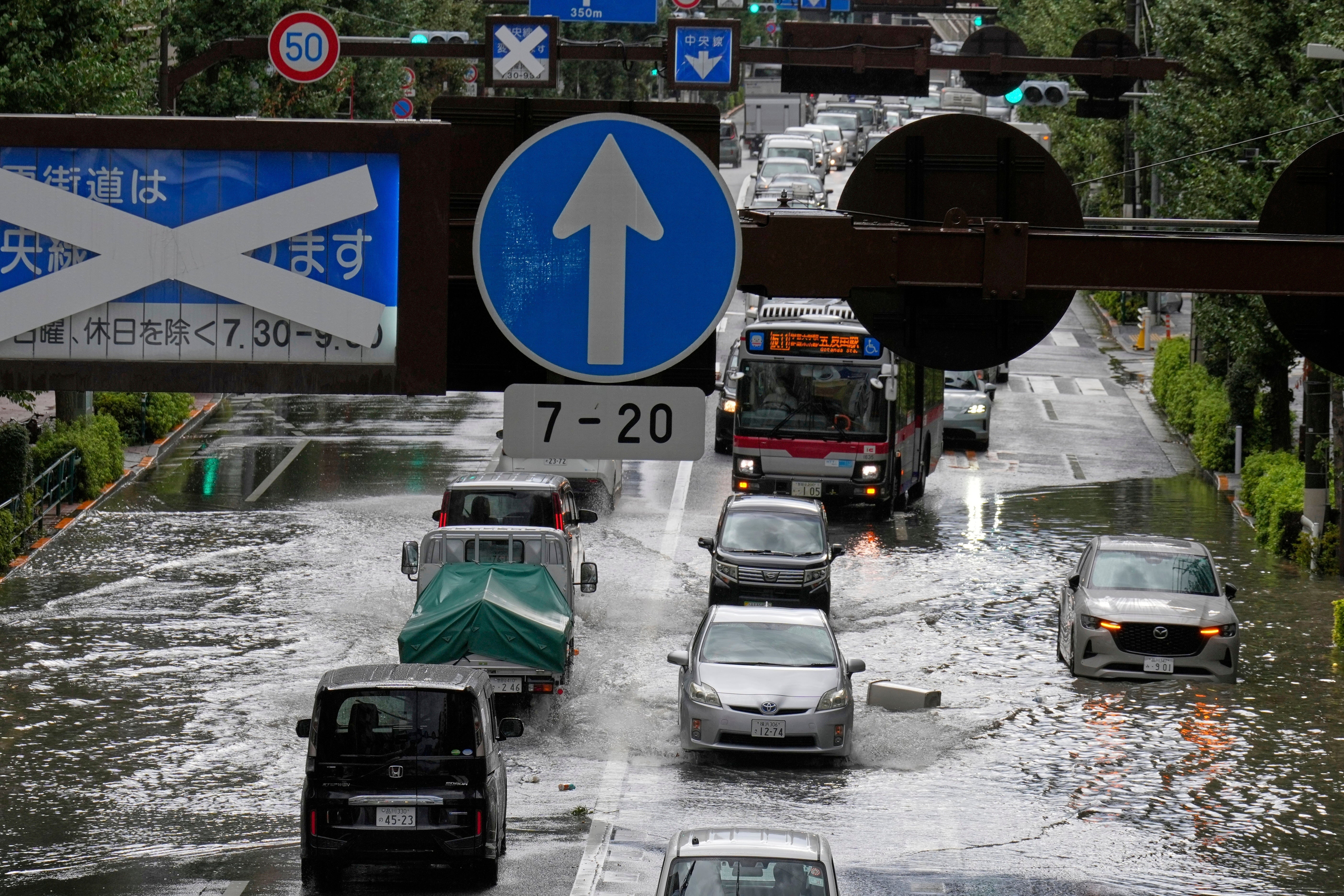 Vehicles drive through a flooded road in Tokyo
