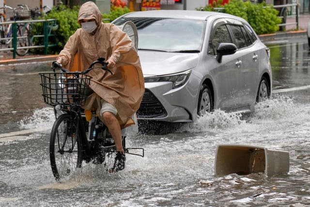 <p>A person rides a bicycle through a flooded road in Tokyo, Japan, on 11 September 2025</p>