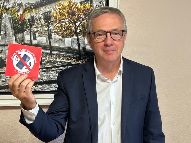 <p>Seine-Port mayor Vincent Paul-Petit holding up a sign that says ‘area without smartphone’</p>