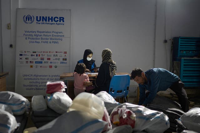 <p>A UN worker assists an Afghan woman and her daughter after they were deported from Iran</p>