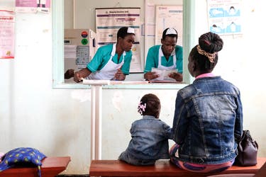 <p>A mother and child wait as medical interns register details of the child before receiving a malaria vaccine in Uganda</p>