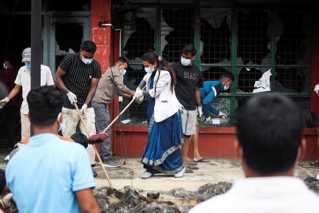 <p>People clean the premises of the Department of Transport Management office in Kathmandu following days of violent protest</p>