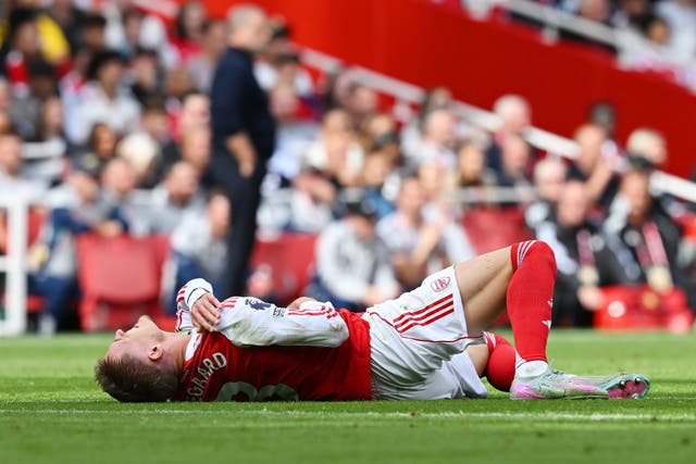 <p>Odegaard clutches his shoulder after a heavy fall </p>
