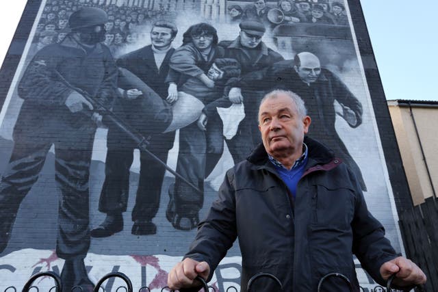 Mickey McKinney, whose brother William was killed on Bloody Sunday, stands beside a mural in the Bogside area of Londonderry, Northern Ireland (PA)
