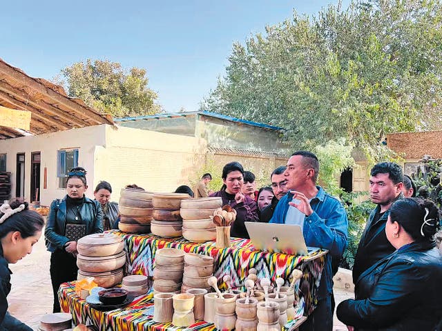 <p>Erxat Ibrayim (third from right) welcomes visitors to his workshop in Hotan prefecture, Xinjiang Uygur autonomous region</p>