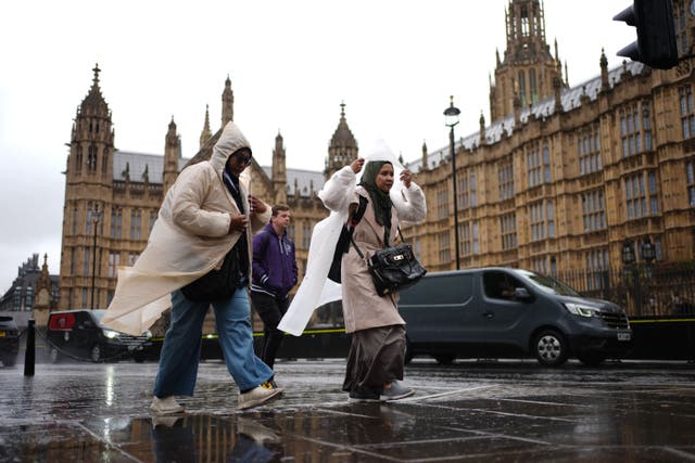 Women shelter from the rain in waterproof coats as they walk through Westminster, central London during a downpour (Ben Whitley/PA)