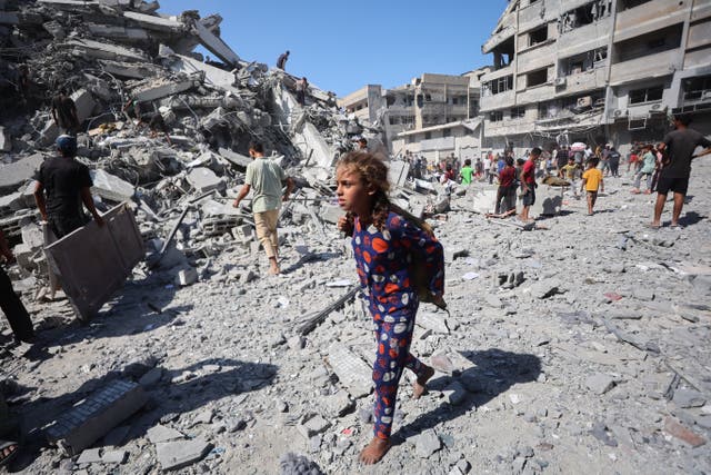 <p>Displaced Palestinians salvage items from the rubble of the al-Ghafari tower after it was destroyed in Israeli strikes in Gaza City on Monday</p>