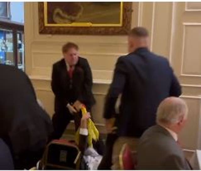 <p>A screenshot from a video showing a protester being dragged out of Windsor Guildhall</p>