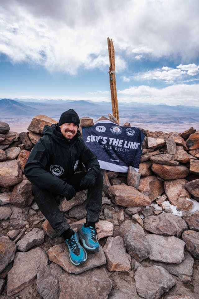 <p>Joshua Patterson sits at the summit after a world-record breaking marathon run over a volcano</p>