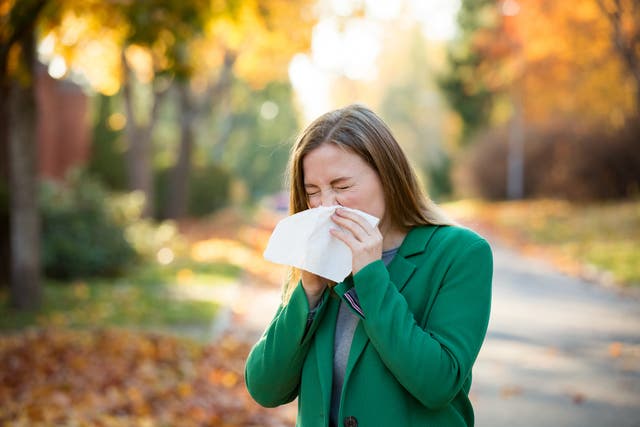 <p>Sick young woman with cold and flu standing outdoors,</p>