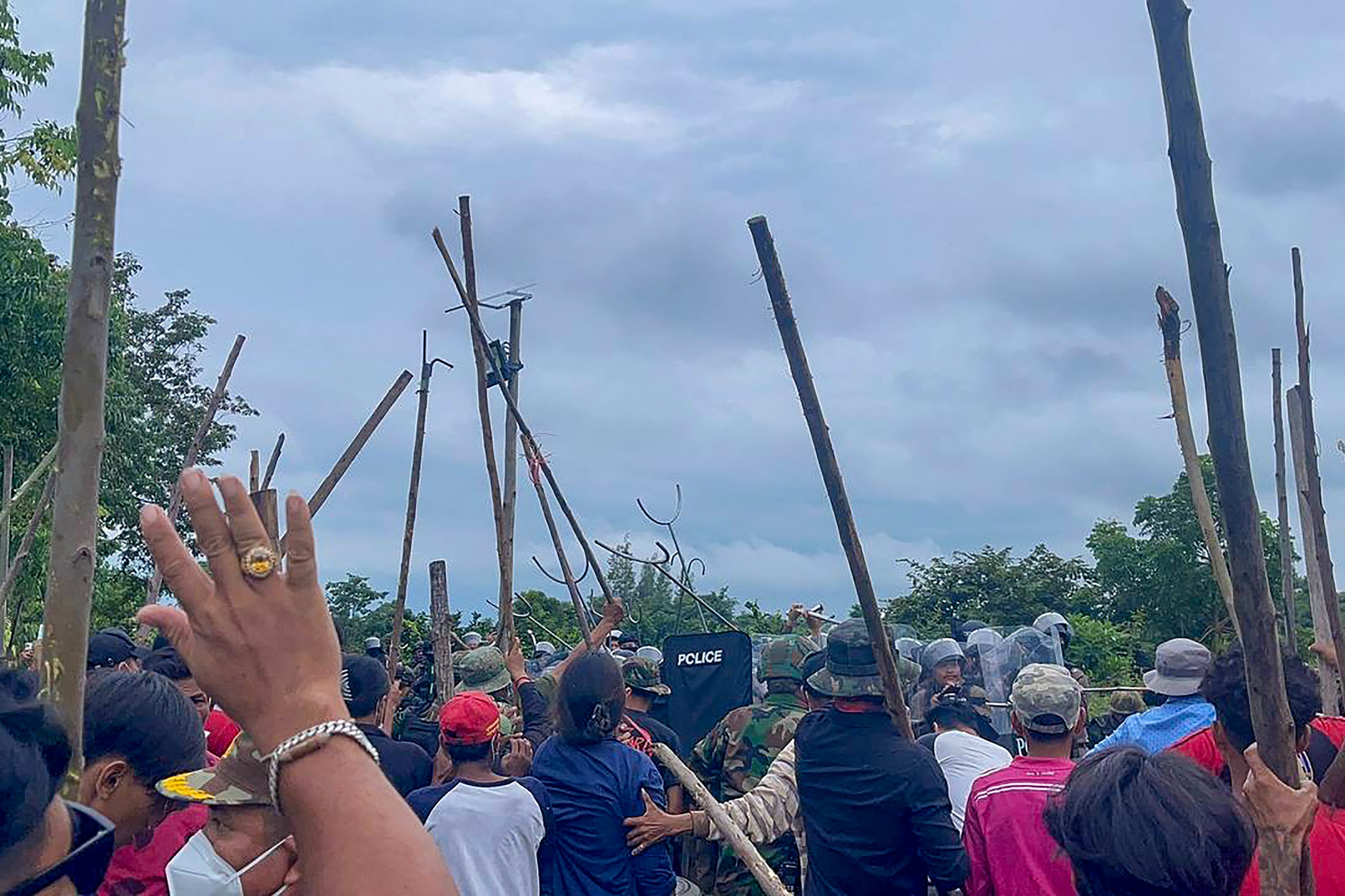 Cambodian people confront Thai police and soldiers in a disputed area along the border in Banteay Meanchey province