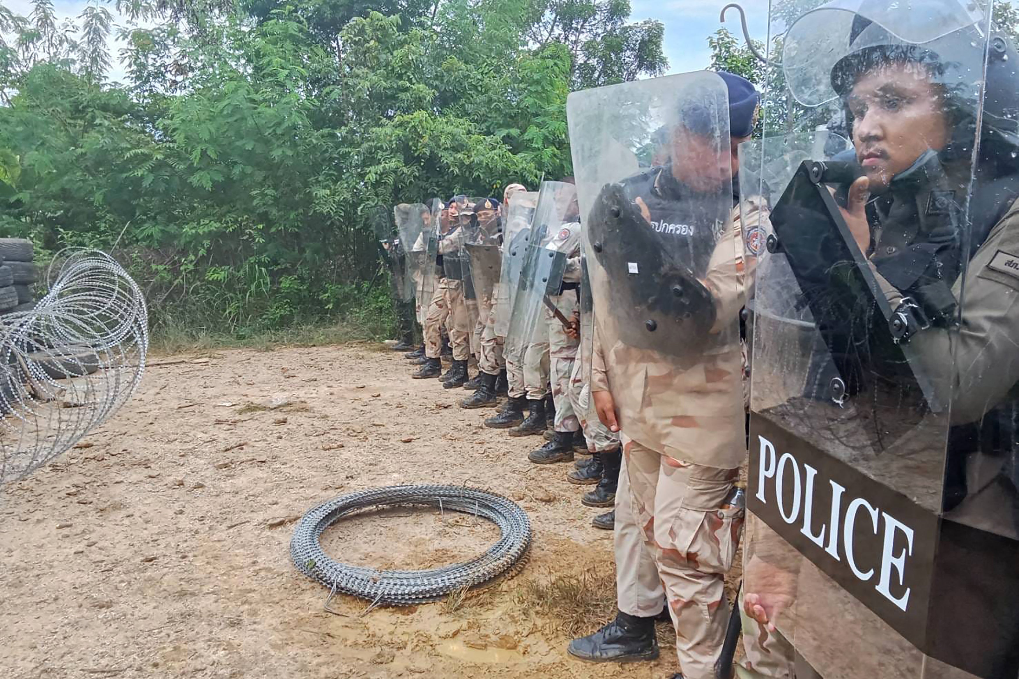 Thai police stand next to barbed wire in a disputed area along the border with Cambodia