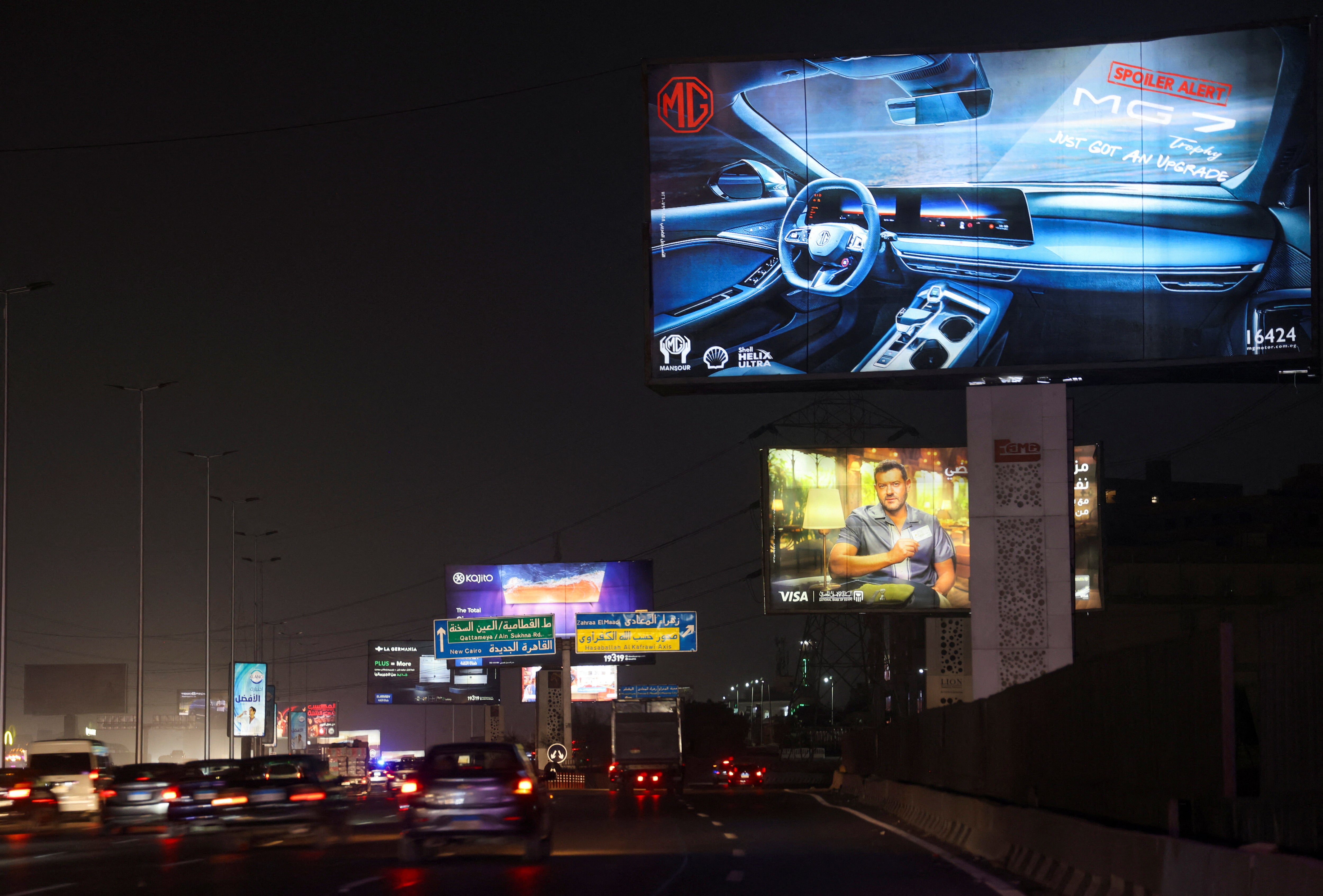 <p>Vehicles drive past brightly lit billboards in Cairo, Egypt</p>