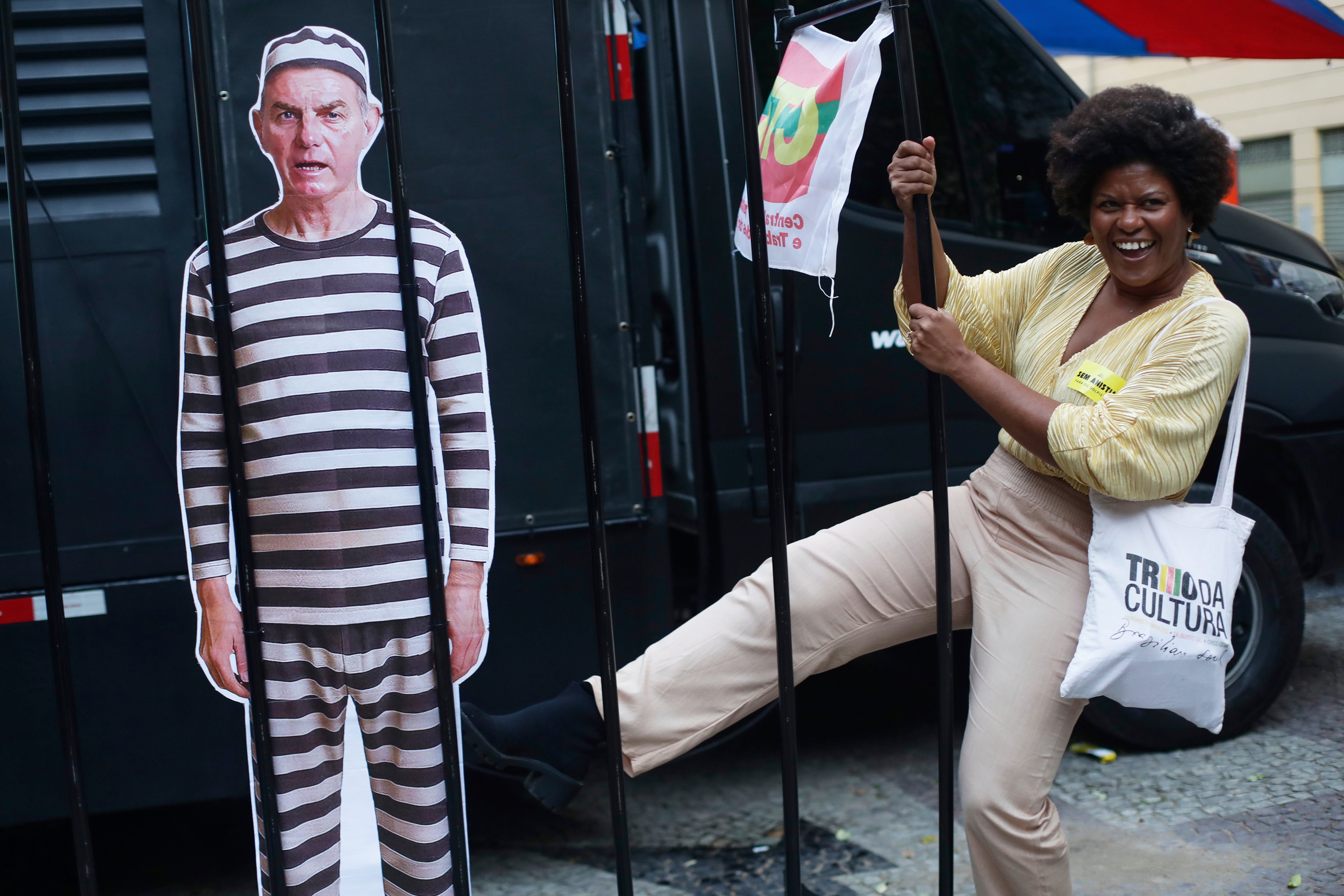 An opponent kicks at a cutout depicting Brazil's former President Jair Bolsonaro in prison garb, as she celebrates a day after the Supreme Court sentenced him to more than 27 years in prison for attempting a coup to remain in office despite his 2022 electoral defeat, in Rio de Janeiro, Friday, Sept. 12, 2025