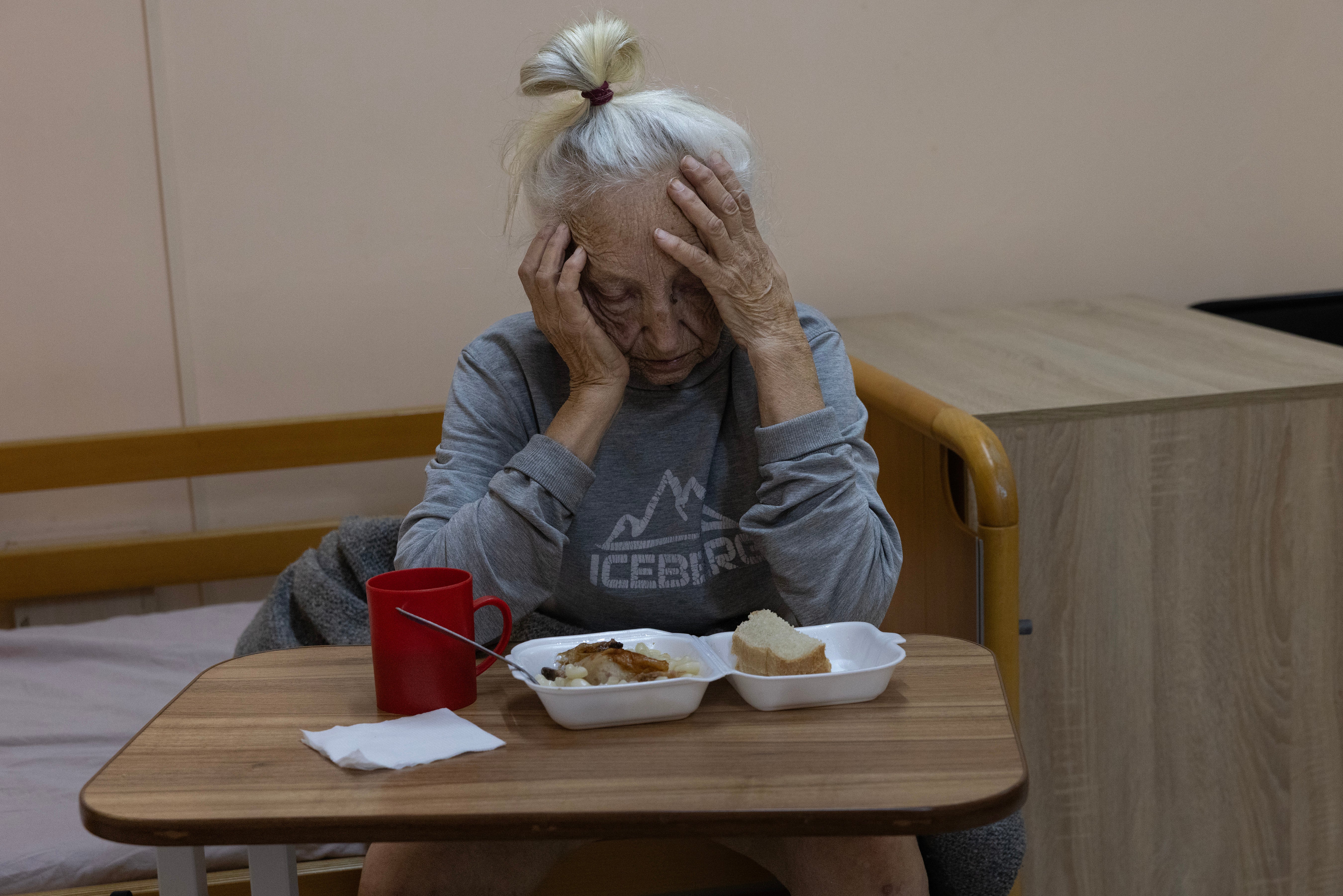 Valentina Miroshnychenko, 86, who has advanced dementia sits on her bed