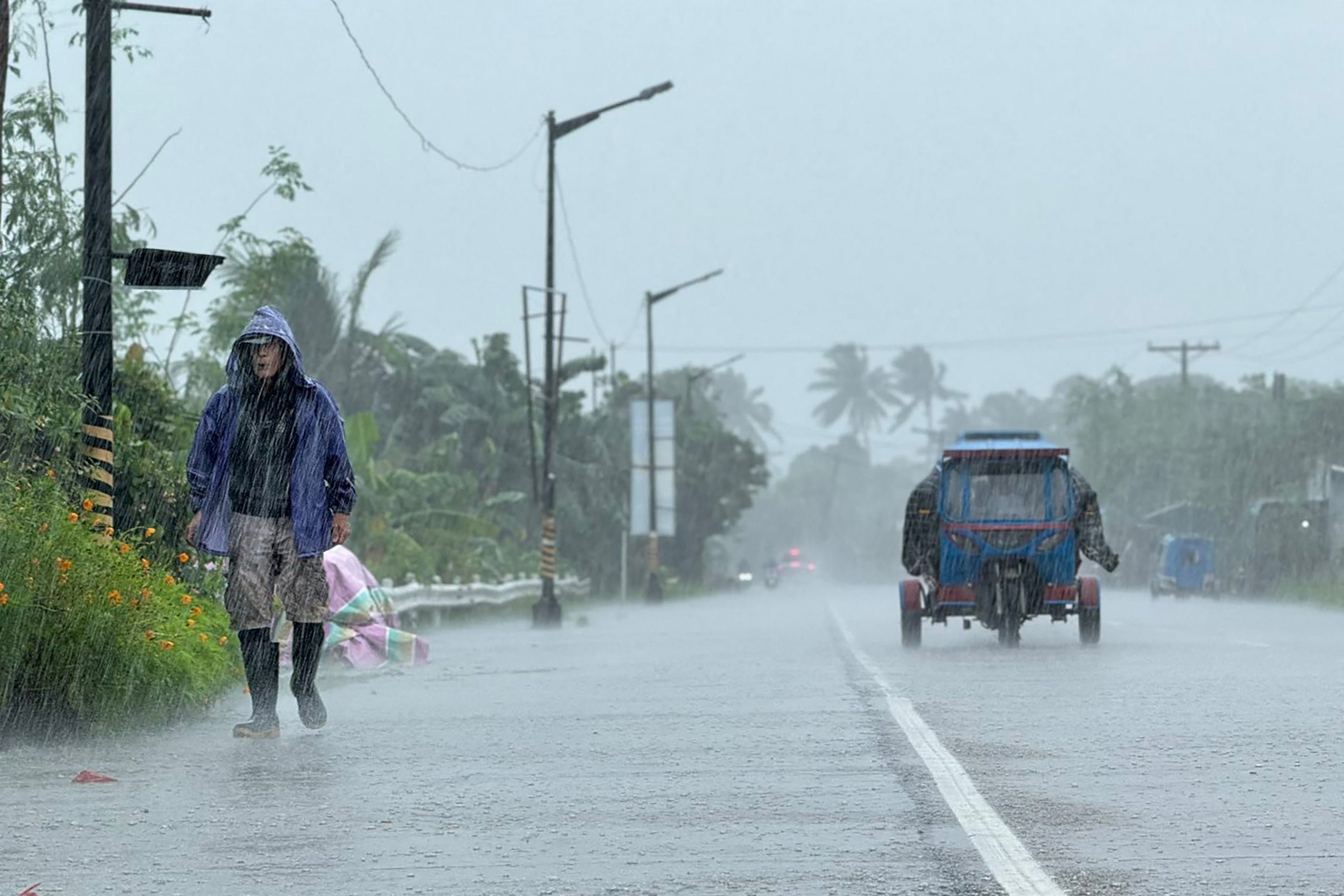 A man walks along a road amid heavy rain due to weather patterns from Super Typhoon Ragasa in Lal-lo town, Cagayan province