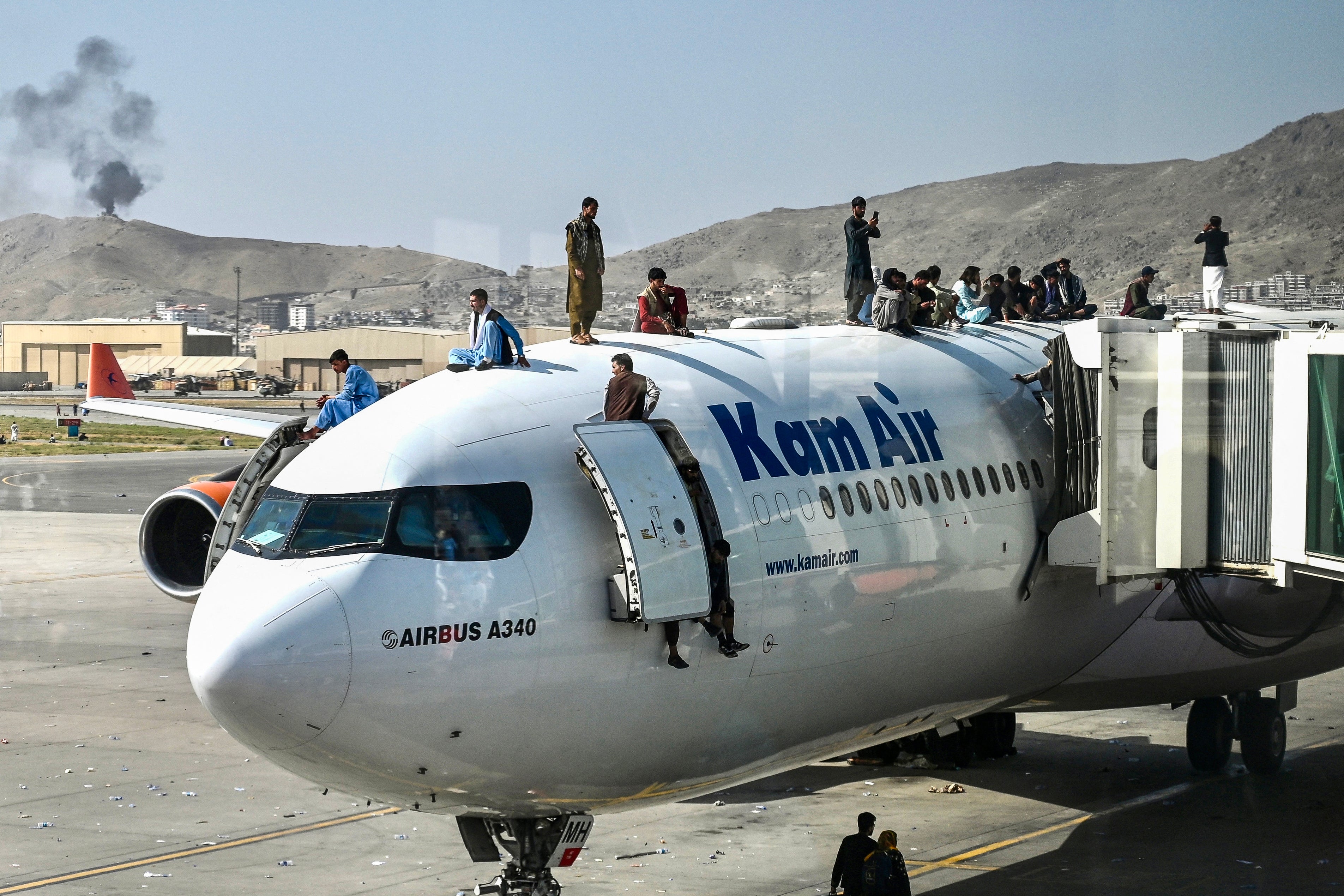 <p>File. Afghans trying to leave the country after the Taliban’s return to power climb atop a Kam Air plane at the Kabul airport on 16 August 2021</p>