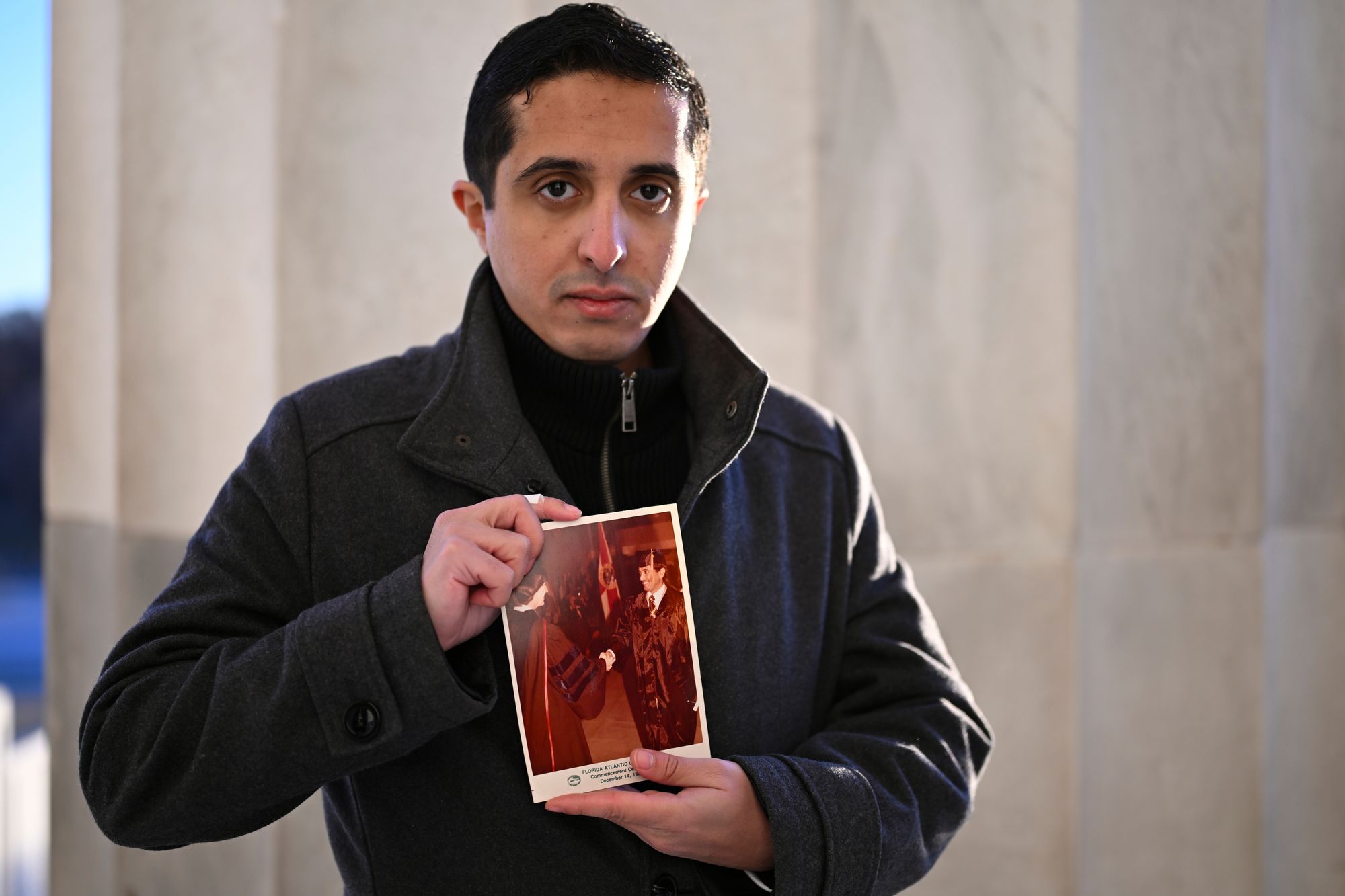 <p>Ibrahim Almadi holds a photo of his father Saad Almadi.</p>
