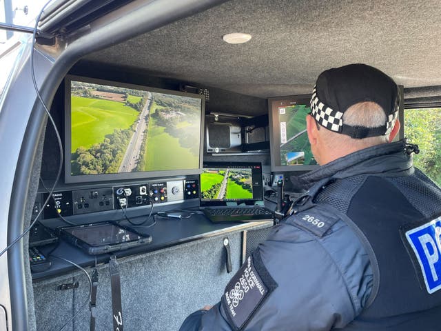 <p>PC Tim Brooks sits inside a police van monitoring footage being captured by a drone above the M5 in Devon</p>