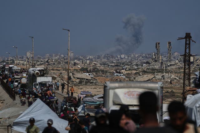 <p>Smoke billows over Gaza City following an Israeli airstrike, as displaced Palestinians flee northern Gaza through Wadi Gaza</p>