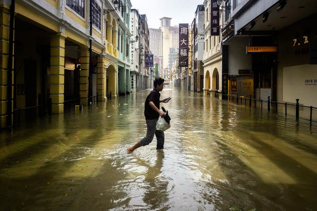 <p>A pedestrian crosses the flooded San Ma Lo commercial area during the passage of Super Typhoon Ragasa in Macau</p>