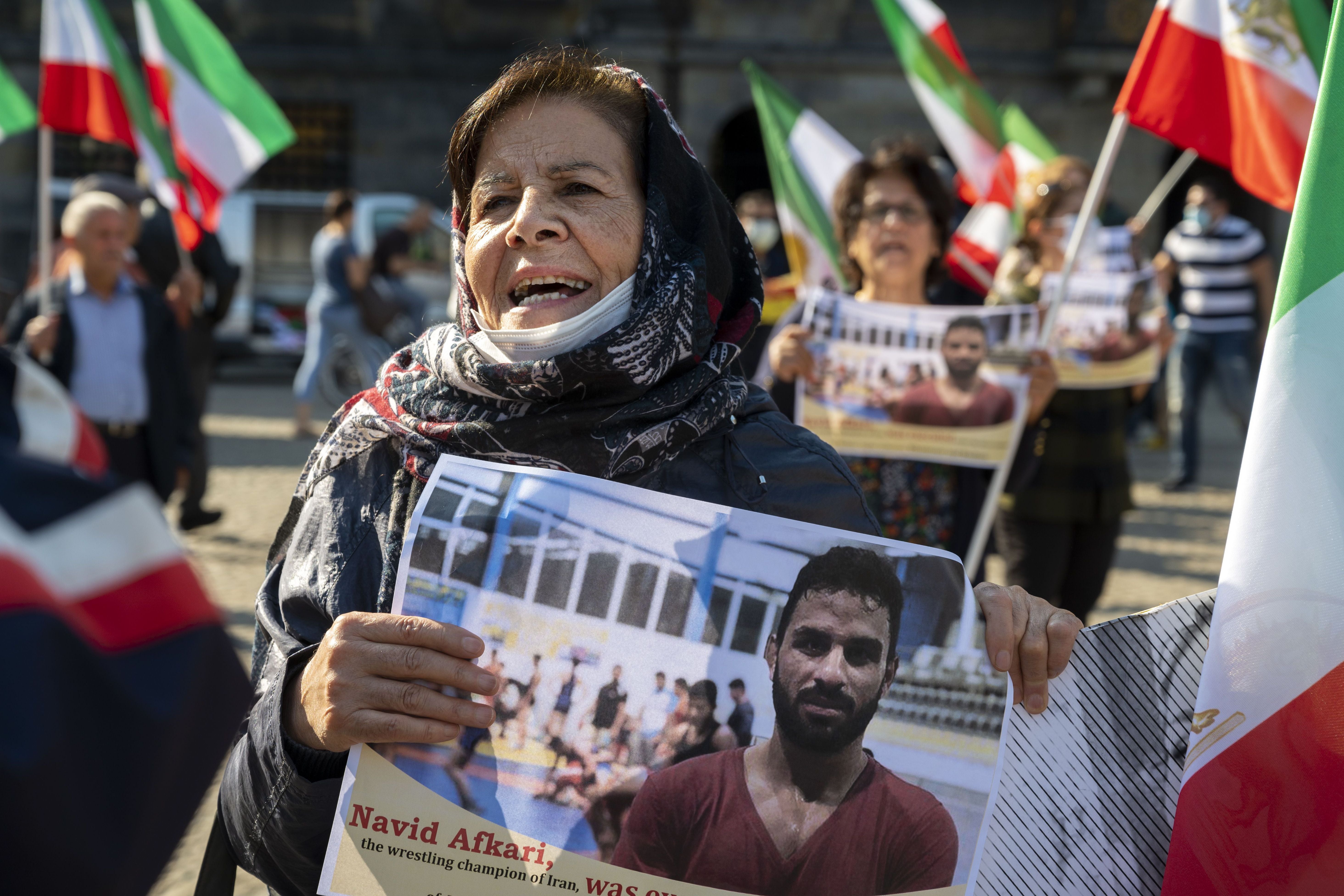 <p>A woman holds a portrait of Iranian wrestler Navid Afkari, who was sentenced to death in 2020</p>