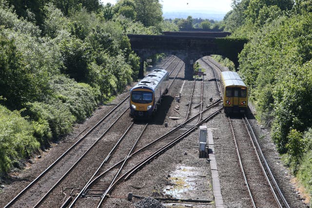 A Merseyrail train (right) travel and a First Transpennine Express pass along track at Hunt’s Cross station (PA)
