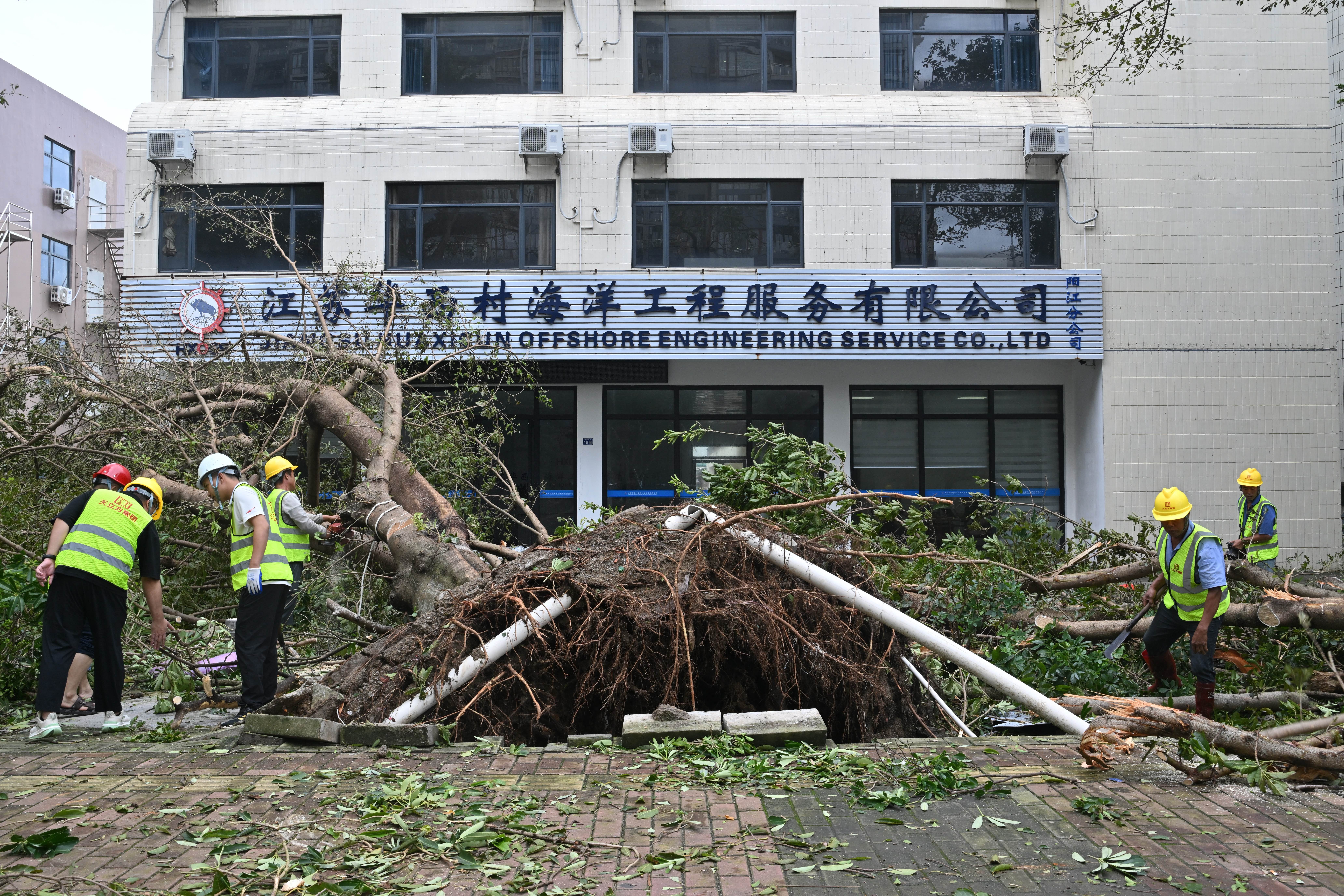 Workers cut and remove a fallen tree following the passage of Super Typhoon Ragasa in Yangjiang, southern China