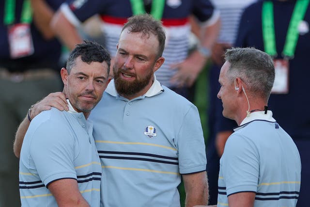 <p>Shane Lowry of Team Europe hugs teammate Rory McIlroy as they talk to Captain Luke Donald of Team Europe</p>