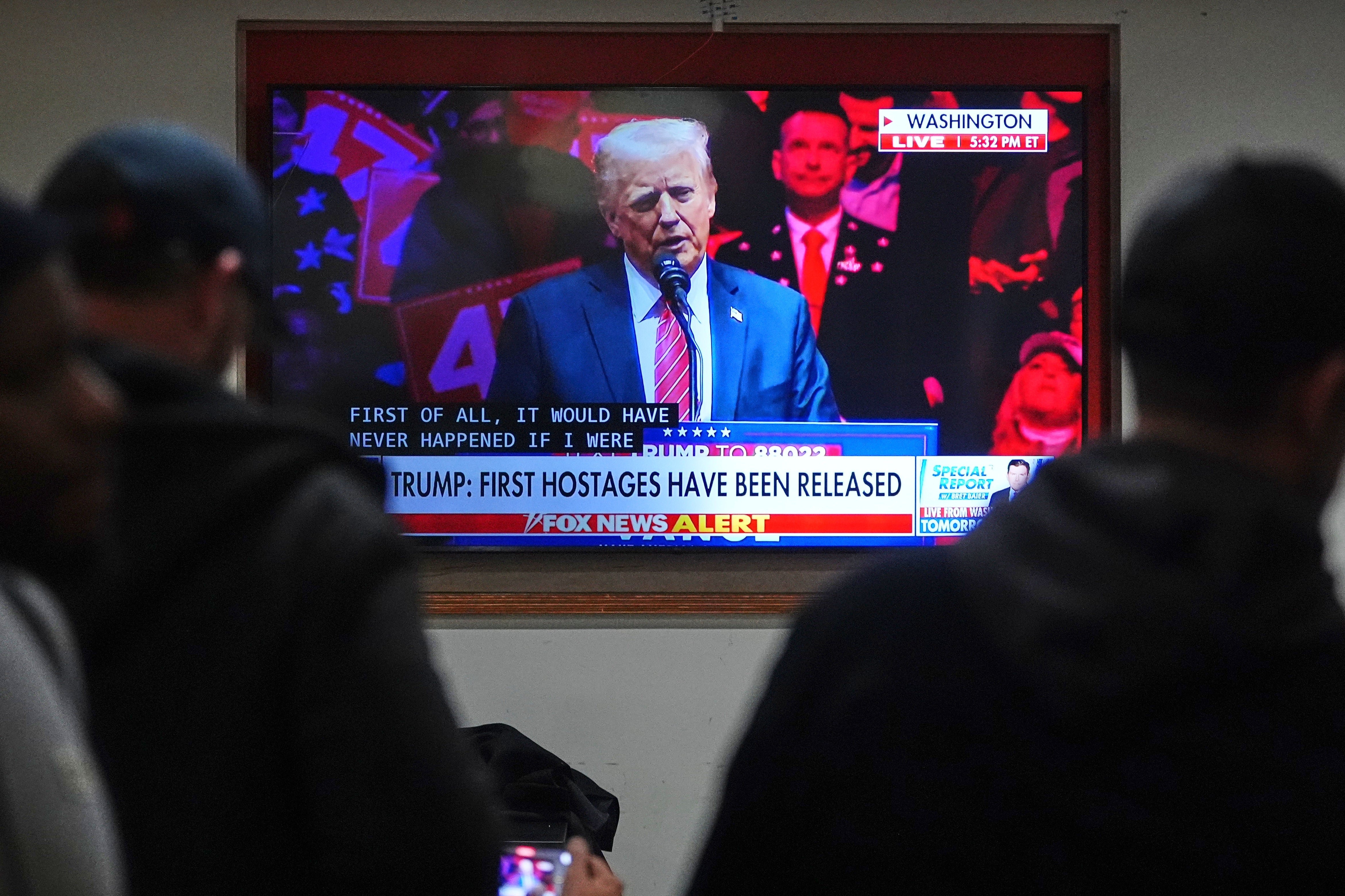 People inside a restaurant watch President-elect Donald Trump on television with subtitles