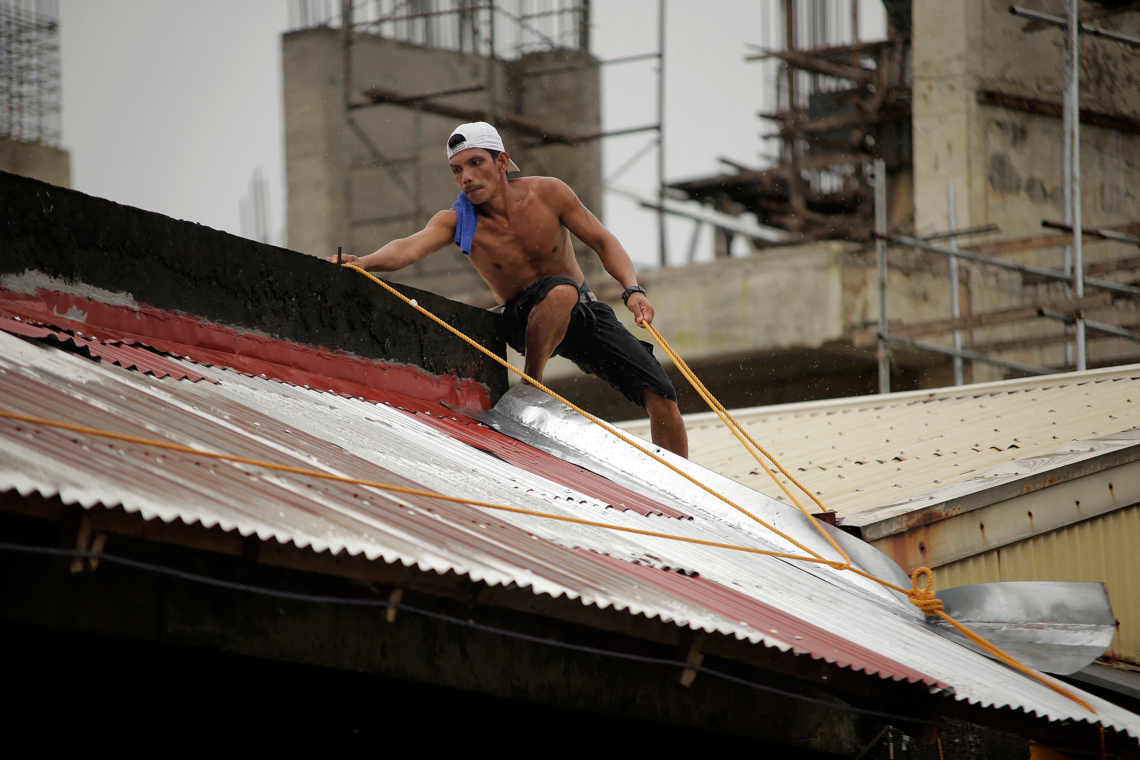 A resident installs a rope on the roof of their house in Legaspi City, Albay province, south of Manila, on 25 September 25, 2025, ahead of Tropical Storm Bualoi's landfall in the Bicol region