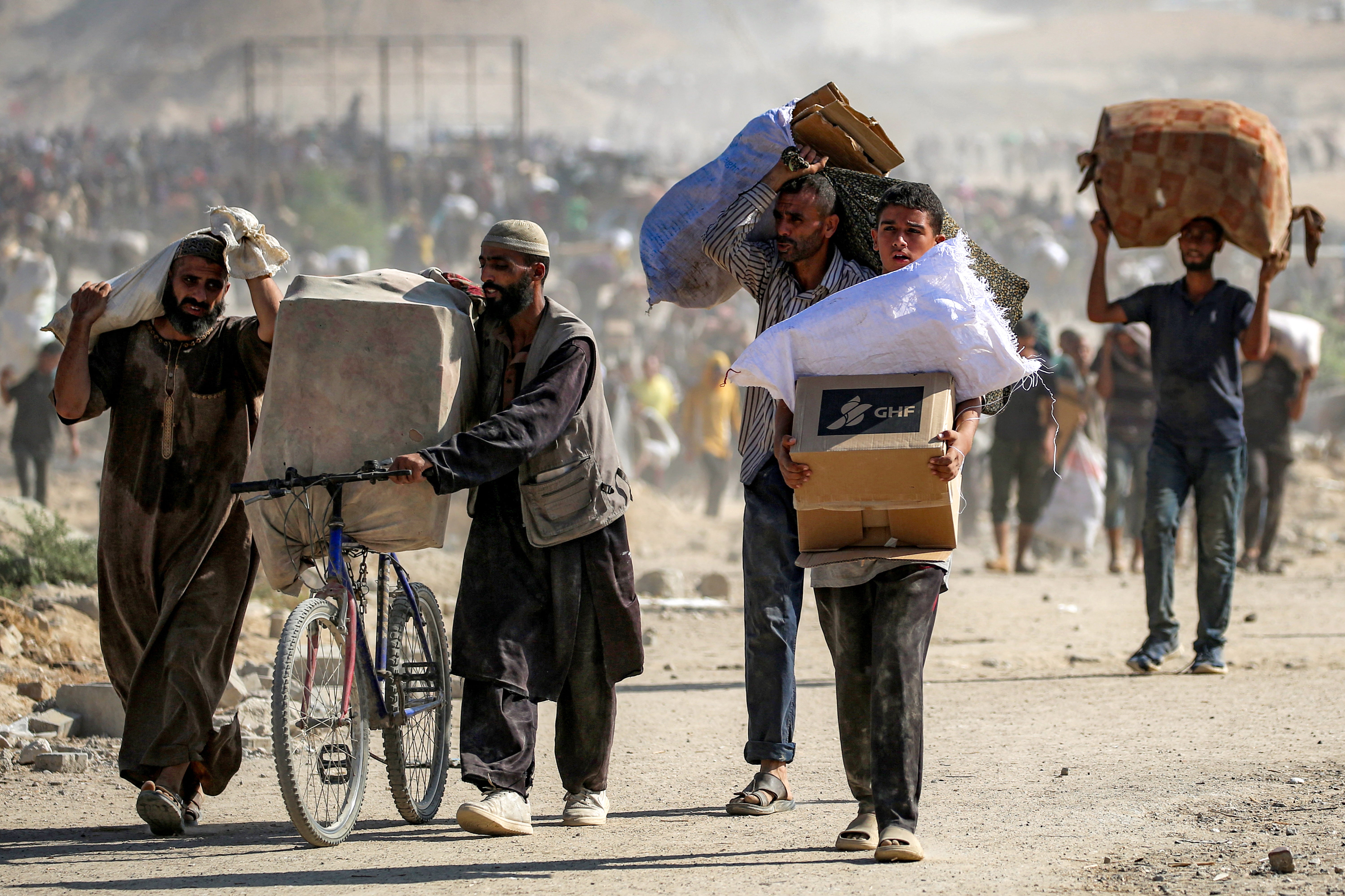 People walk with humanitarian aid packages that they received from a distribution centre run by the US and Israeli-backed Gaza Humanitarian Foundation (GHF), at the so-called 