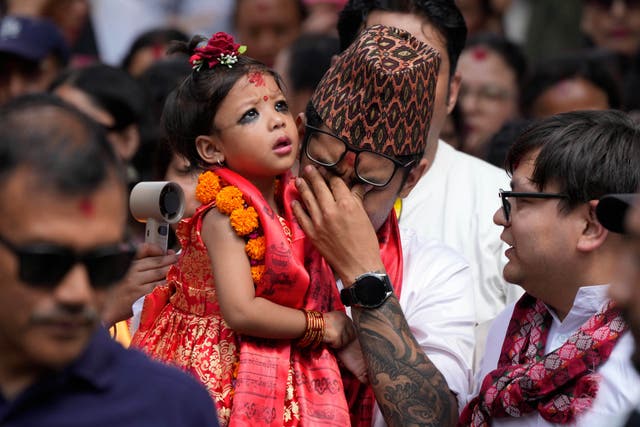<p>Nepal's newly appointed living goddess, Kumari Aryatara Shakya, is carried by her father as they walk towards Kumari Ghar</p>