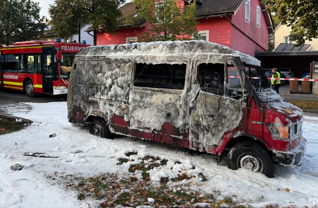 <p>A burnt van covered in extinguishing foam following the blast</p>