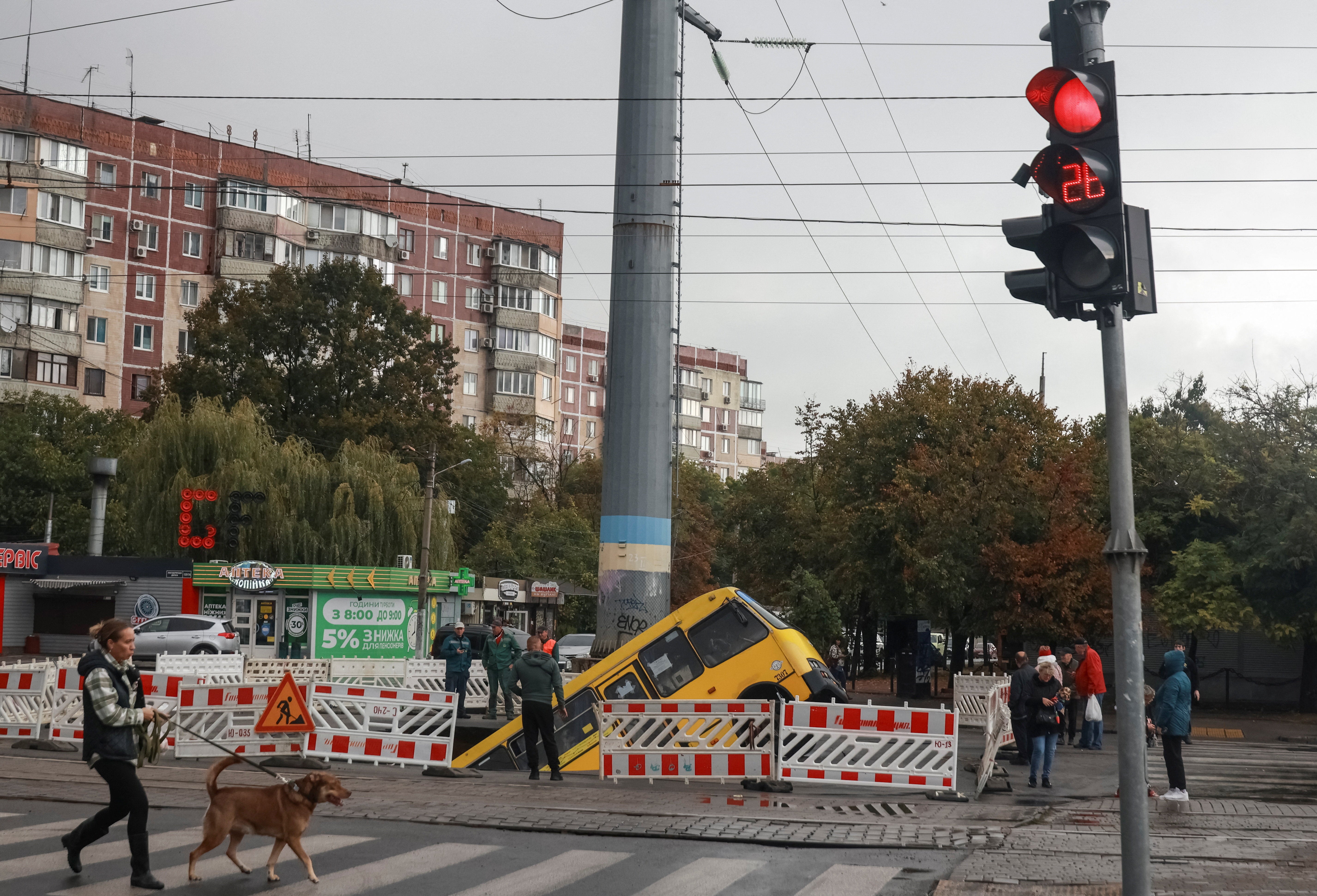 A bus is seen stuck in a huge hole that has opened at a road, following major rainfall in Odesa